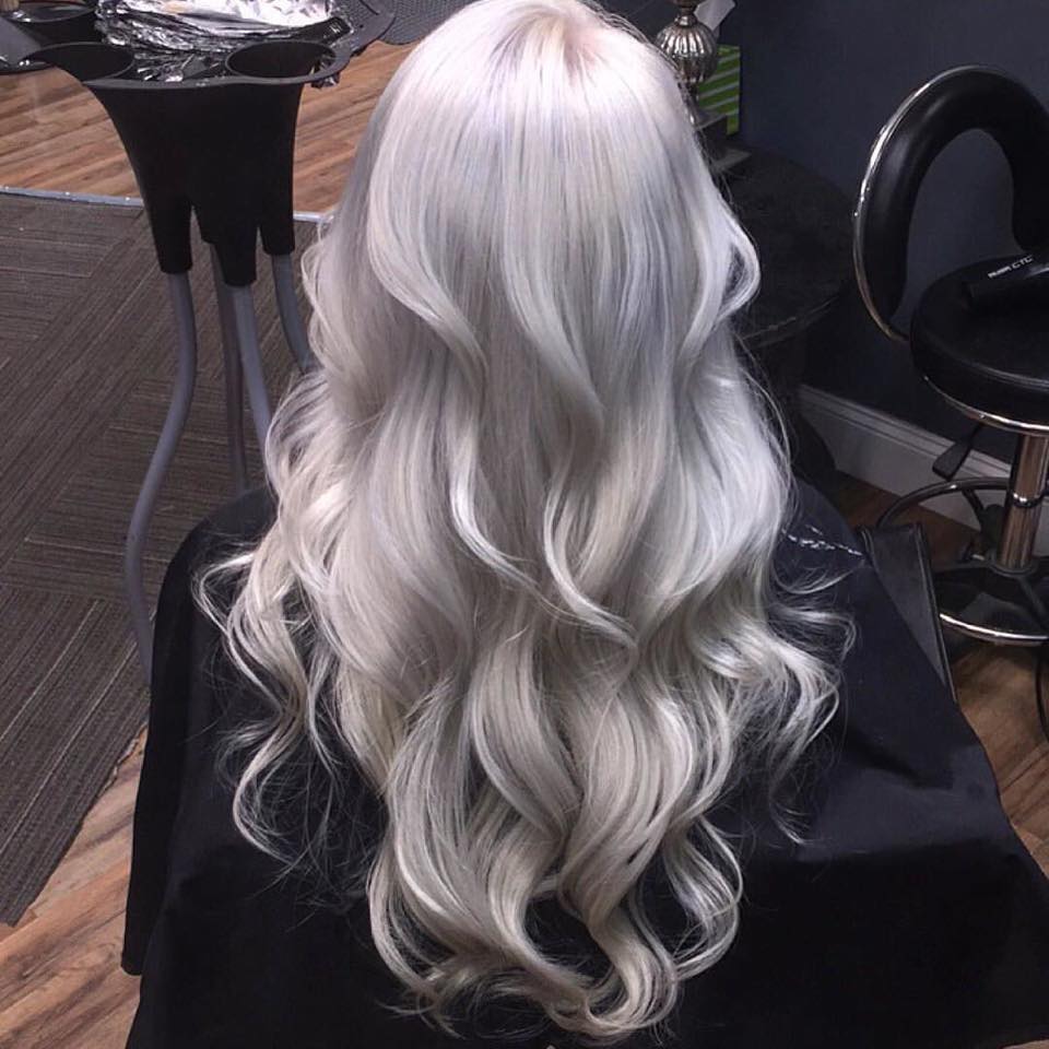 Person with long, wavy, platinum blonde hair sitting in a salon chair.