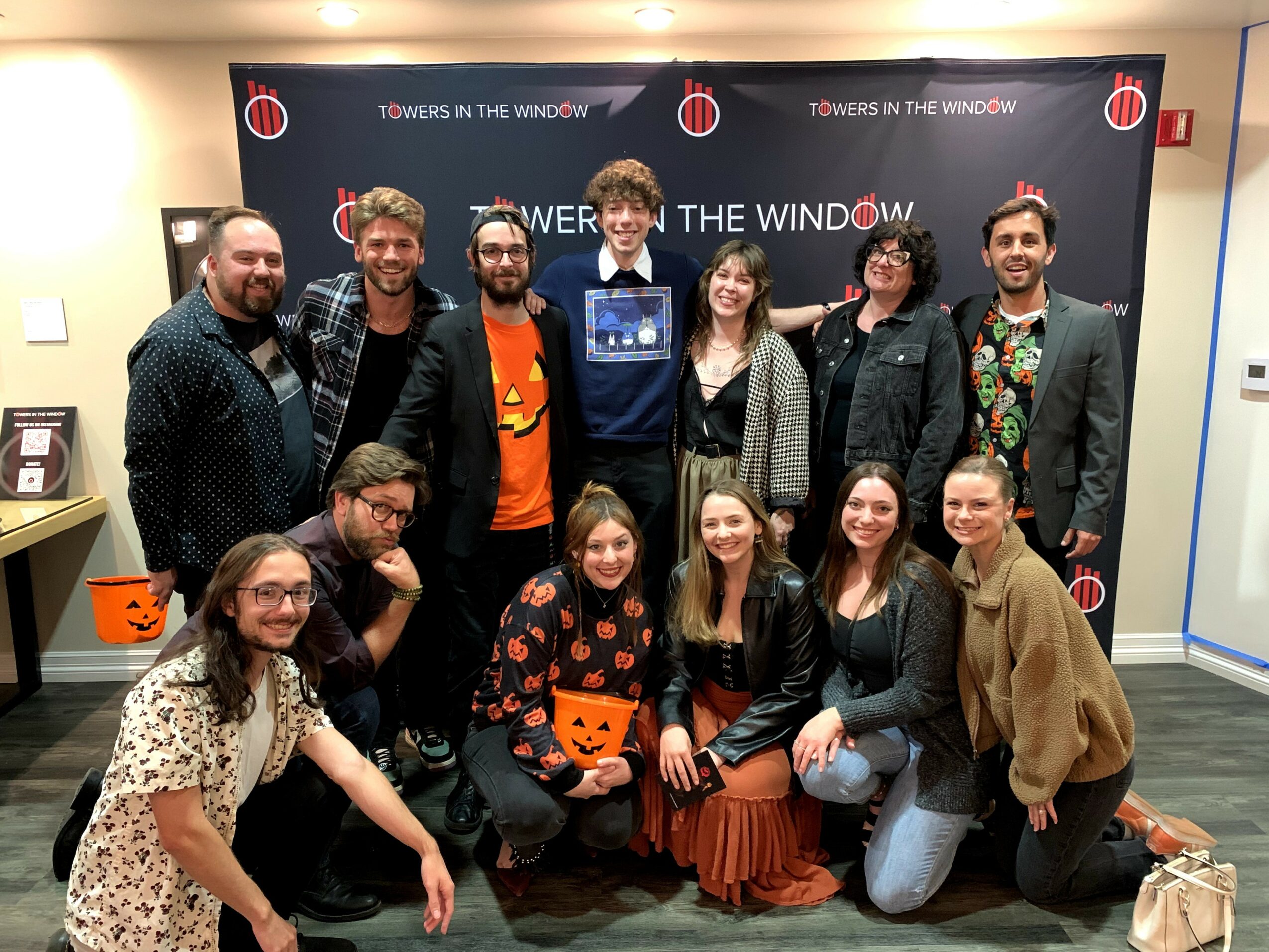 Group of eleven people posing indoors in front of a backdrop with the text 'TOWERS IN THE WINDOW'.