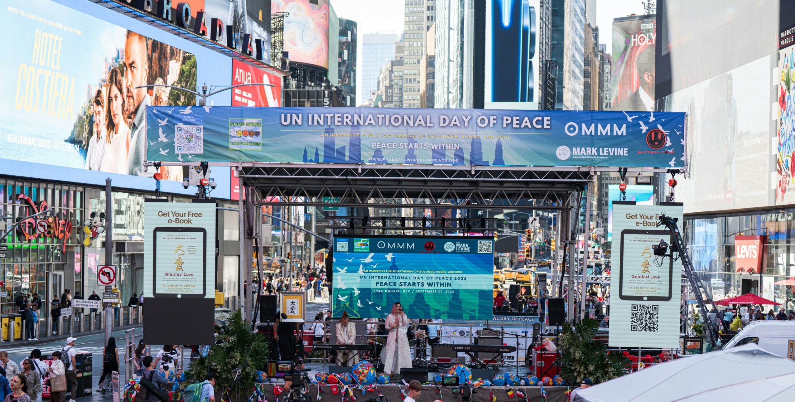 Stage set up in a busy city square with banners and screens for UN Peace Day event.