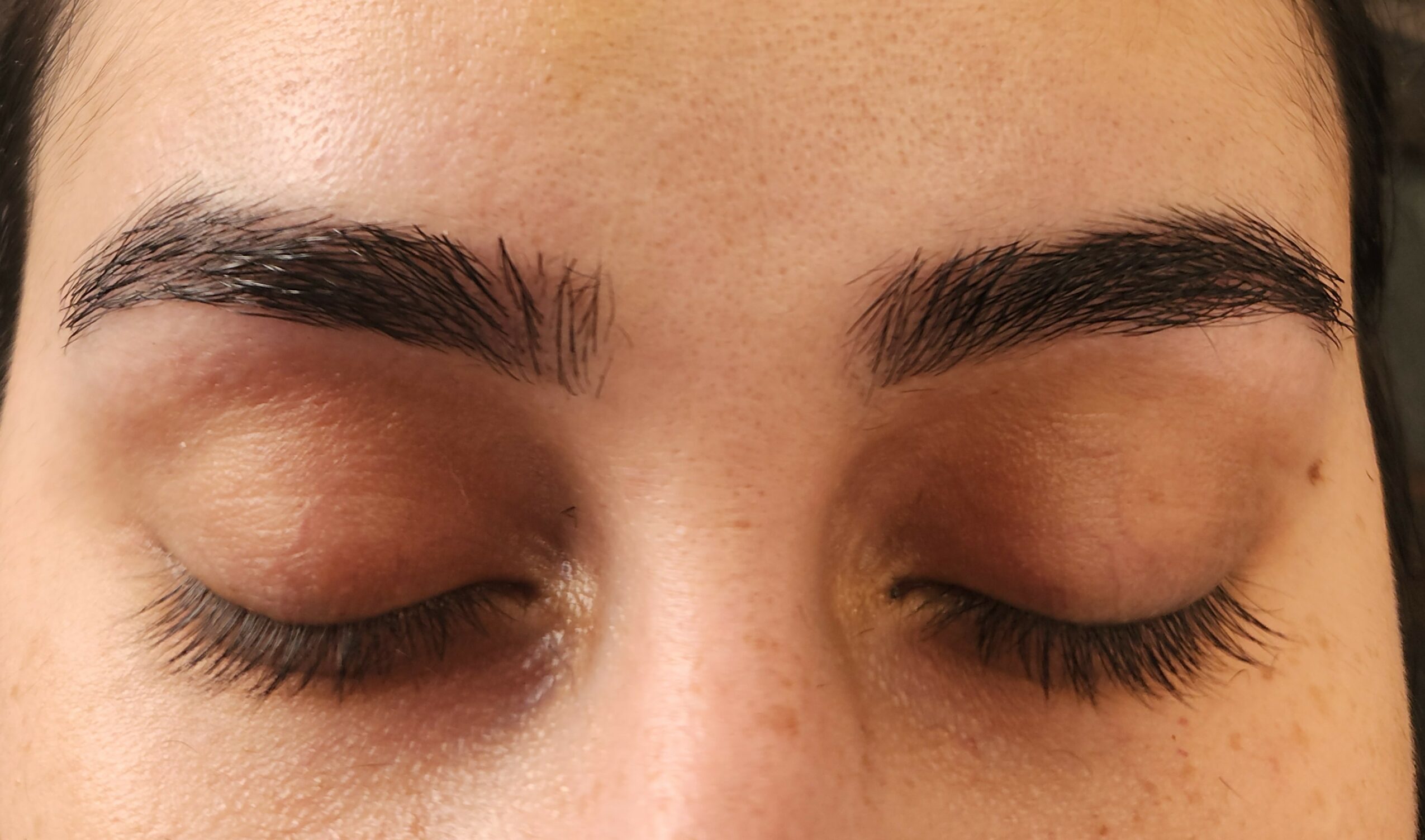Close-up of closed eyes with well-groomed eyebrows and long eyelashes.