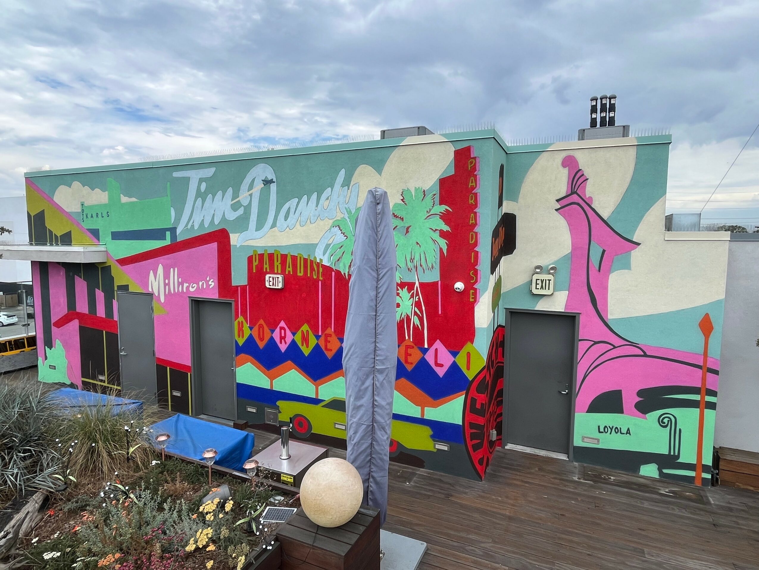 Colorful mural on building wall with abstract shapes, a large pink figure, and text reading 'Time Dance'.