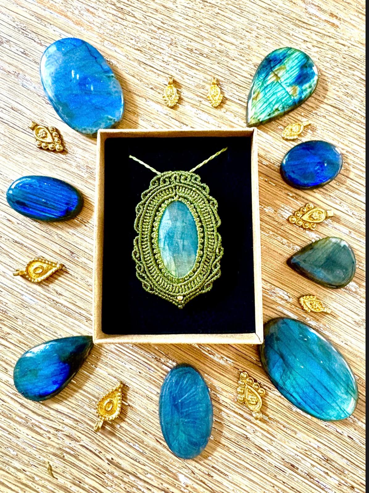 Jewelry with a pendant featuring a large blue gemstone, surrounded by blue and green stones and gold accents on a wooden surface.