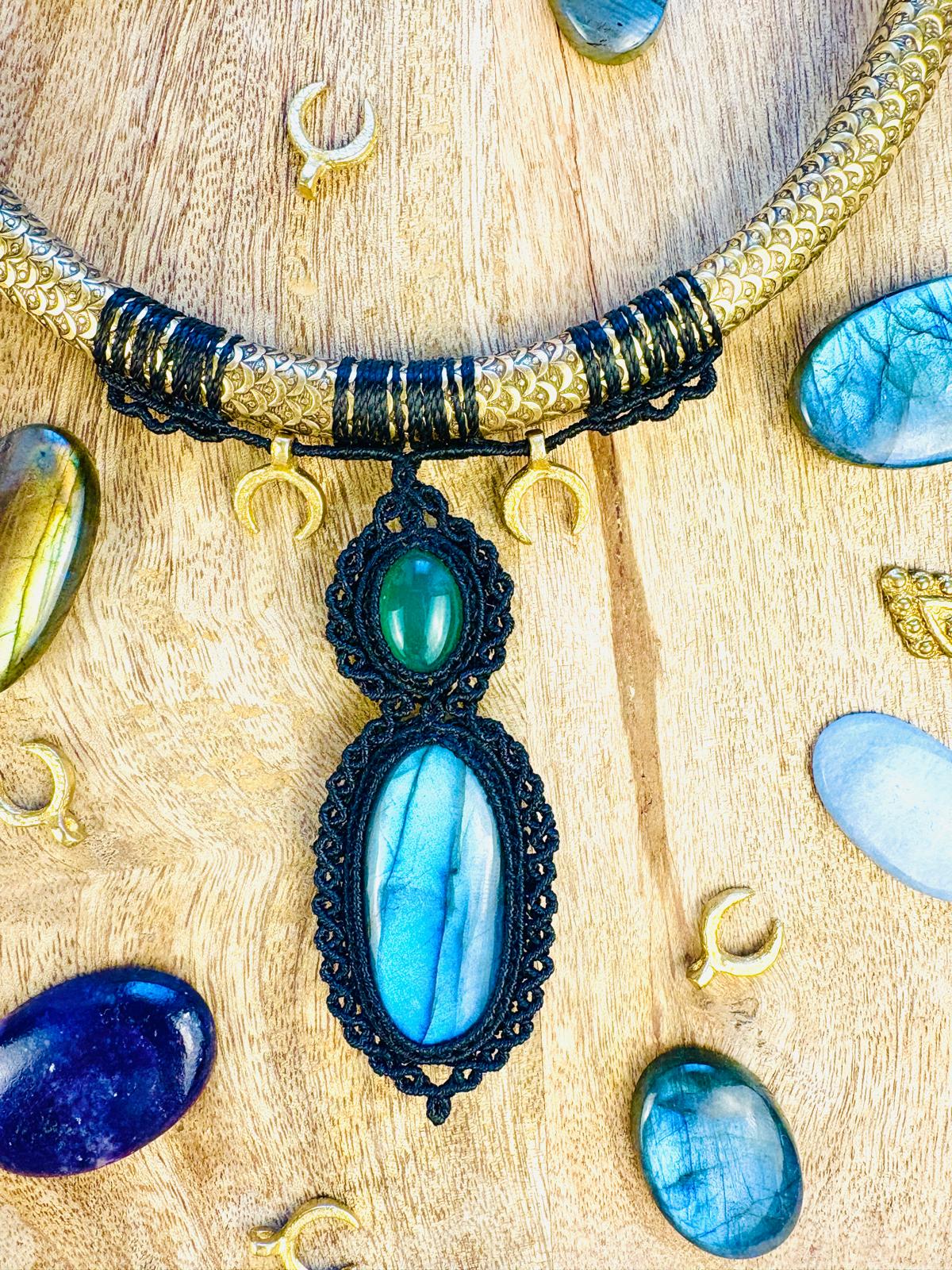 Pendant necklace with blue and green stones, surrounded by small jewelry pieces on a wooden surface.