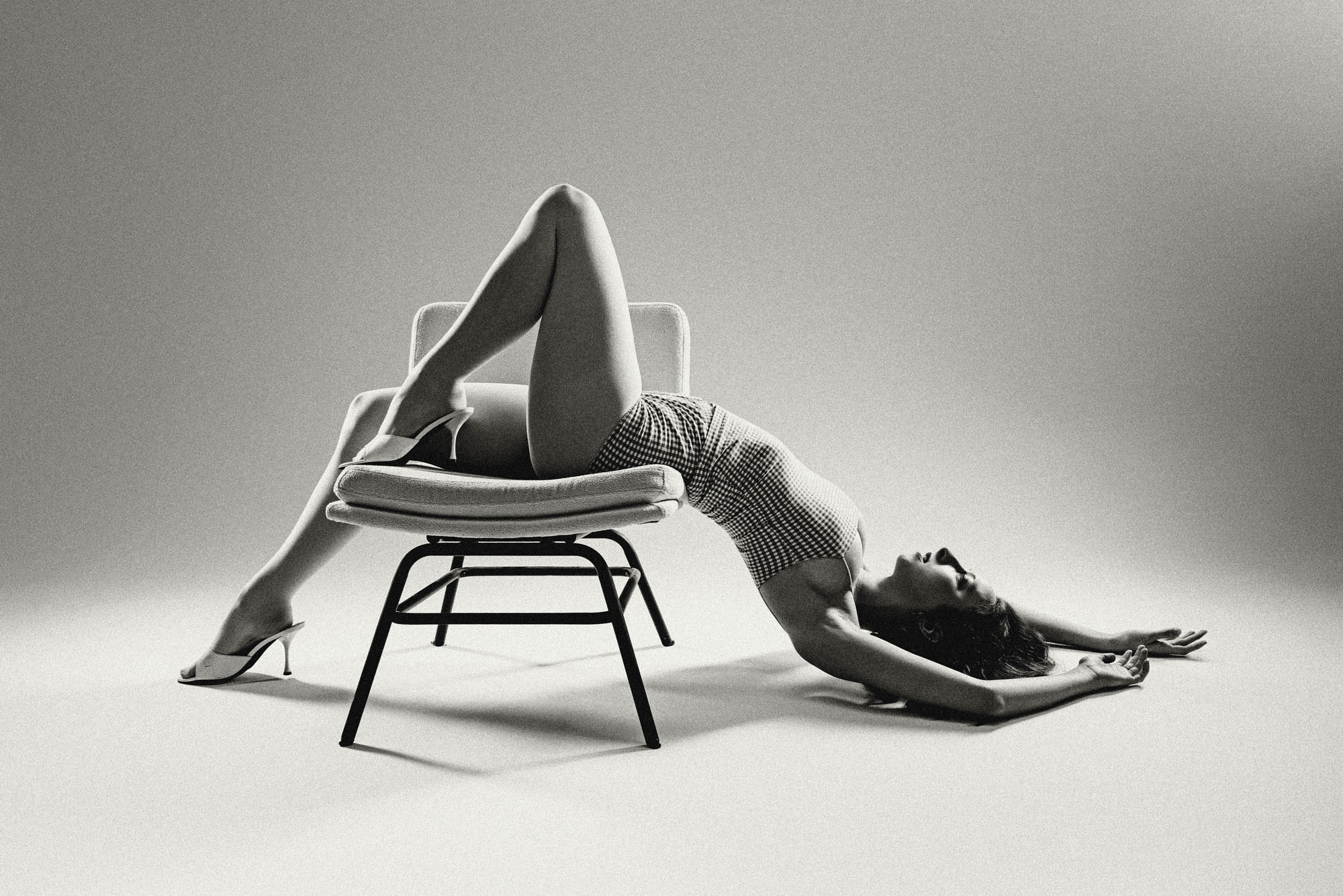 Person performing a backbend with legs on a chair and arms on the floor, in a studio setting.