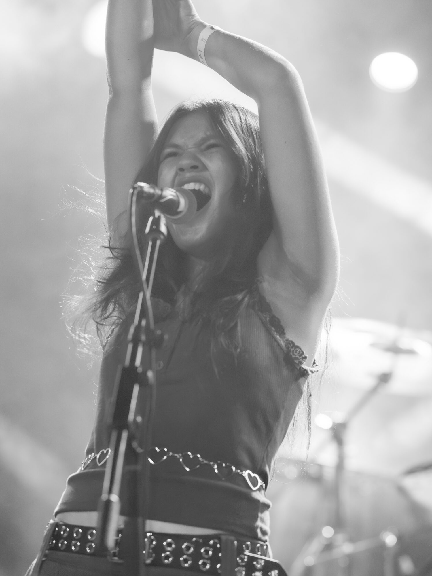 Female singer passionately performs on stage with arms raised, microphone in front, and stage lights in background.
