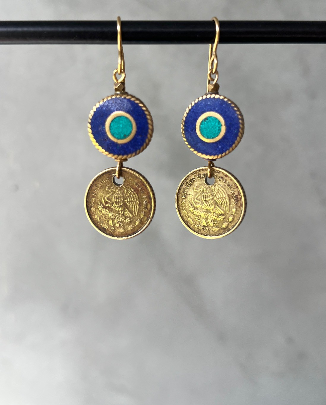 Gold coin earrings with blue and turquoise circular accents hanging from hooks.