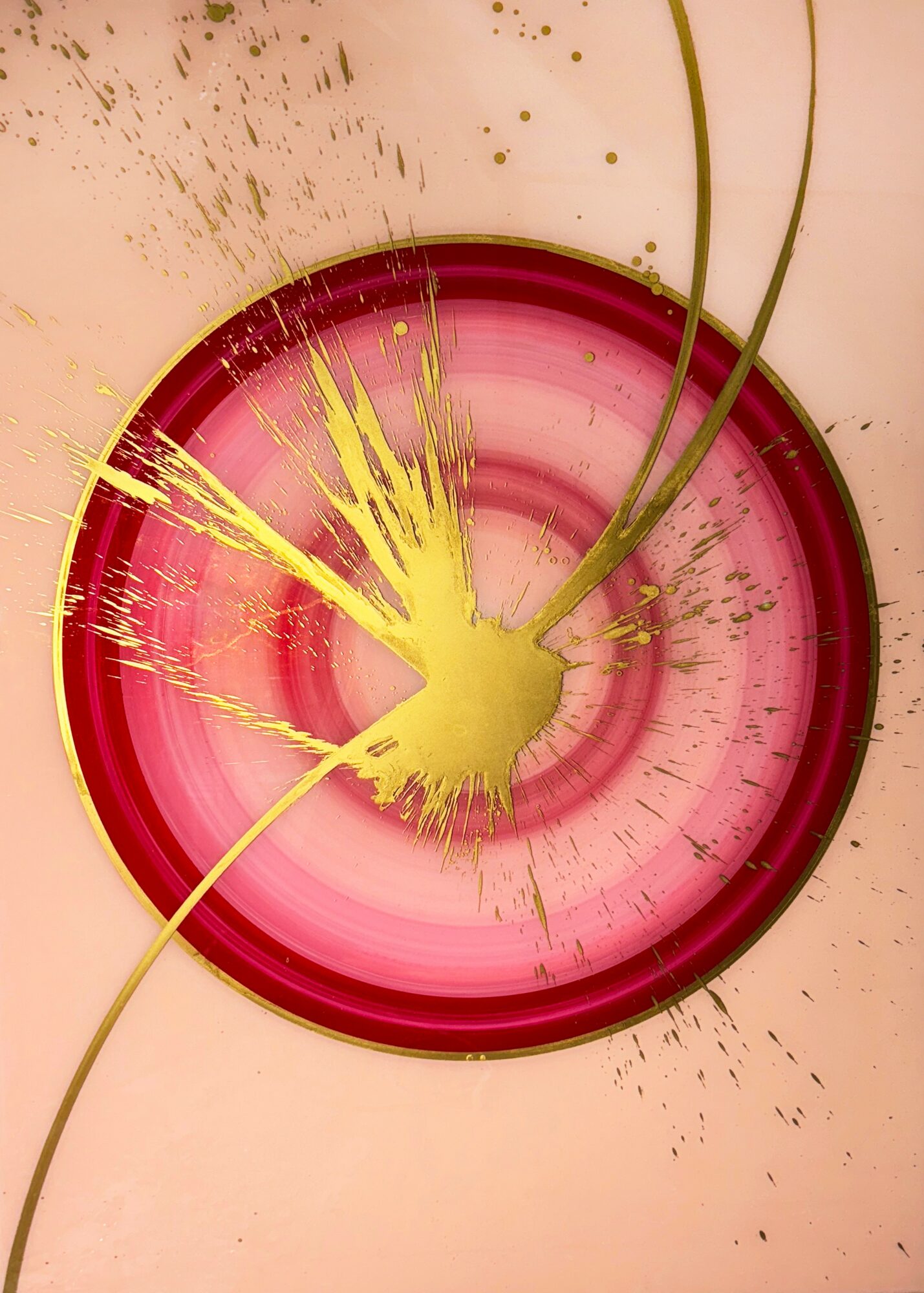 Pink circular object with yellow paint splatter and two thin green lines extending from the center.