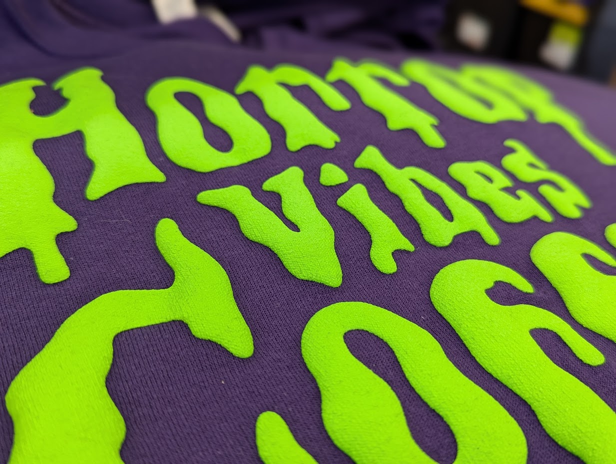 Close-up of fabric with bright green text on a purple background.