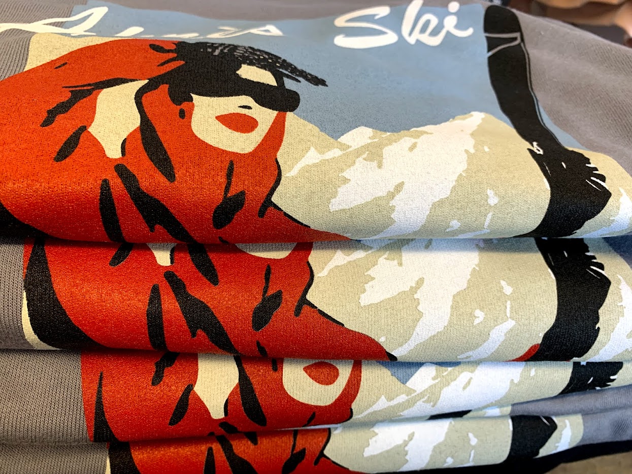 Close-up of fabric with a colorful graphic design featuring a person with glasses and mountain scenery.