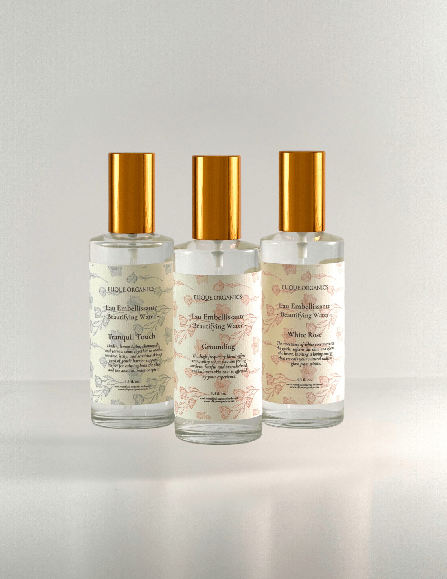 Three clear bottles with gold caps arranged in a row on a white surface, labels with text visible.