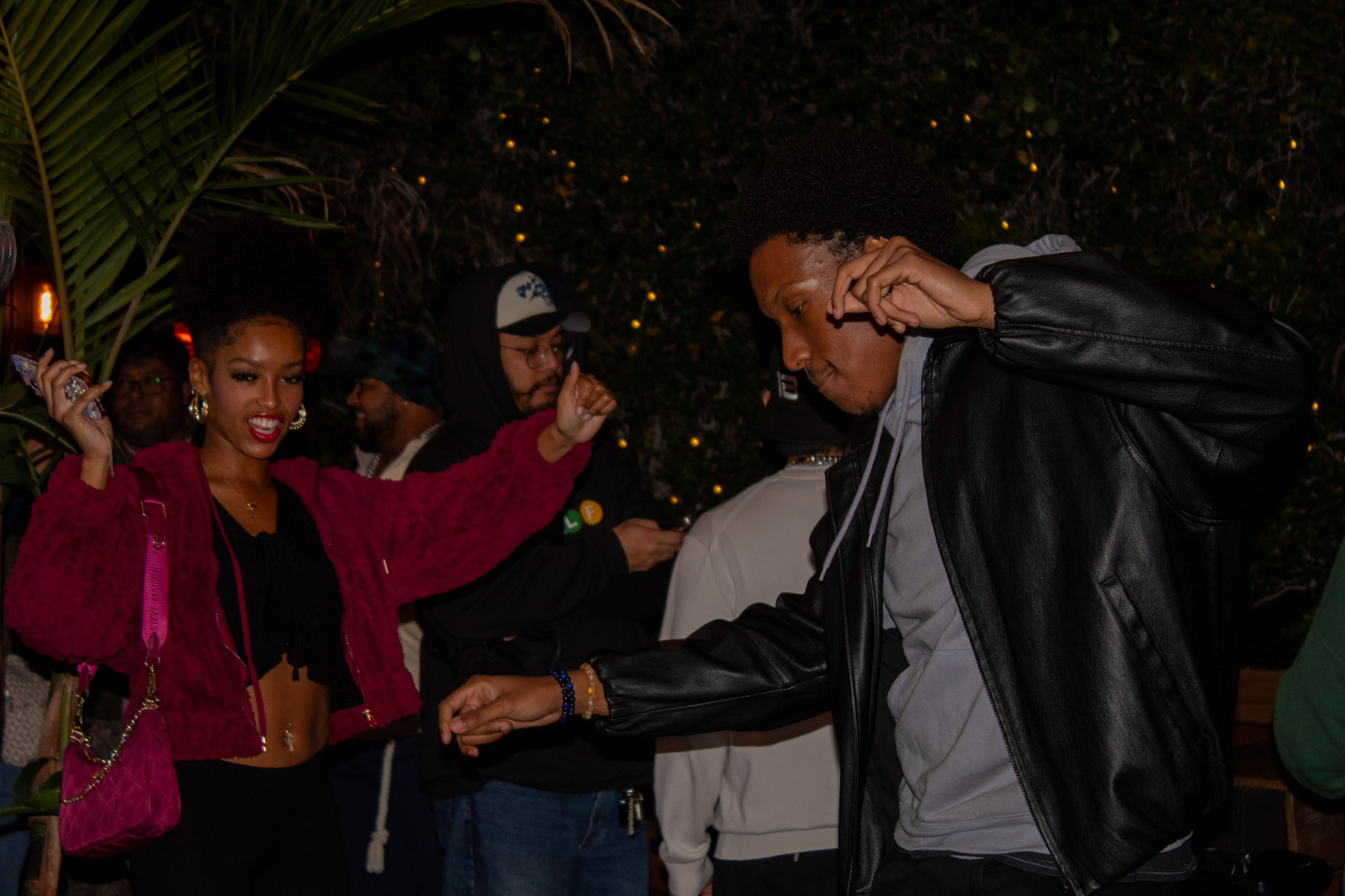 Group of people dancing outdoors at night, smiling and enjoying themselves.