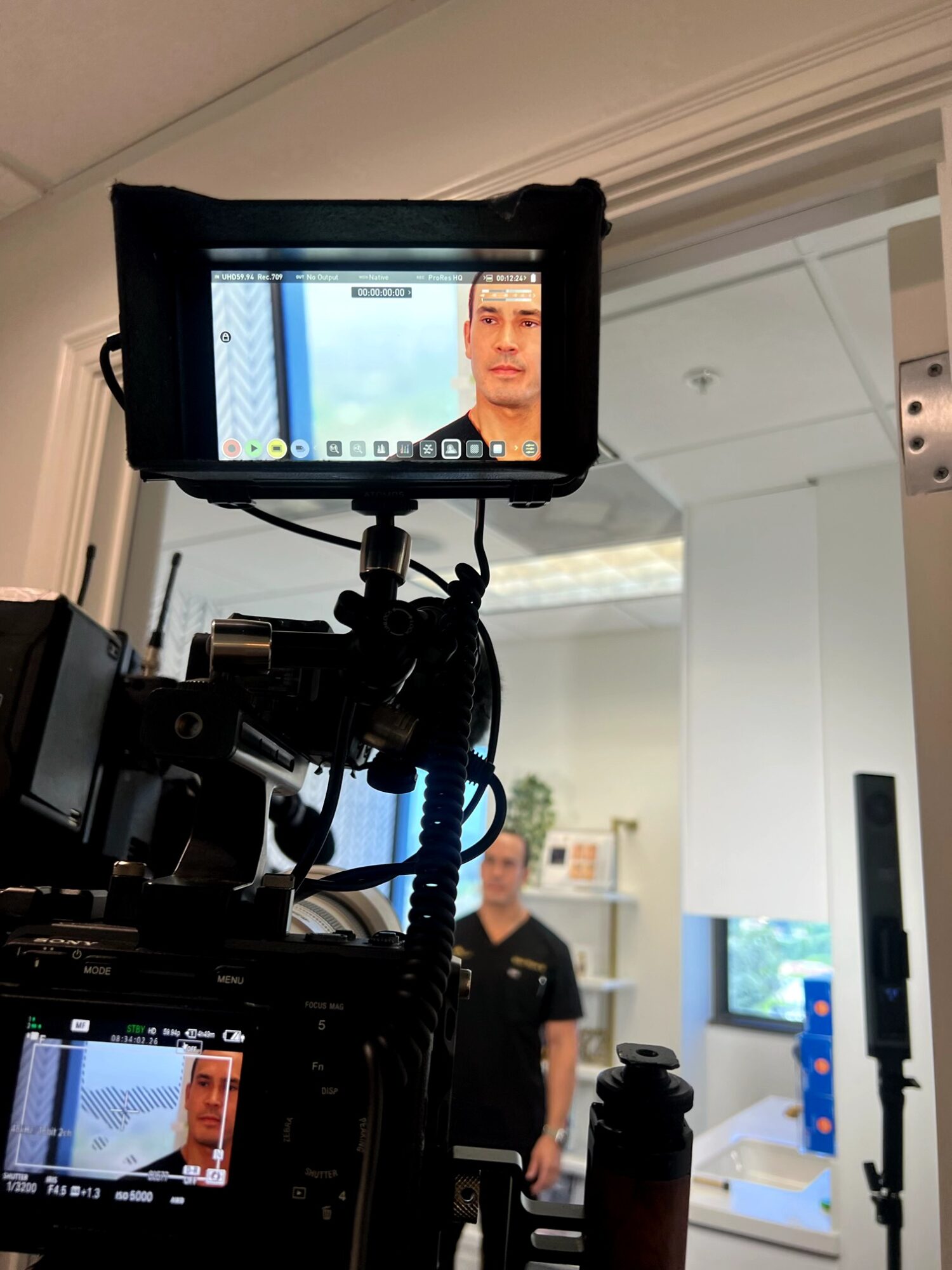 Camera setup capturing a person standing in a room with white walls and furniture.
