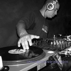 DJ wearing headphones operates turntable and mixer in a dark setting.