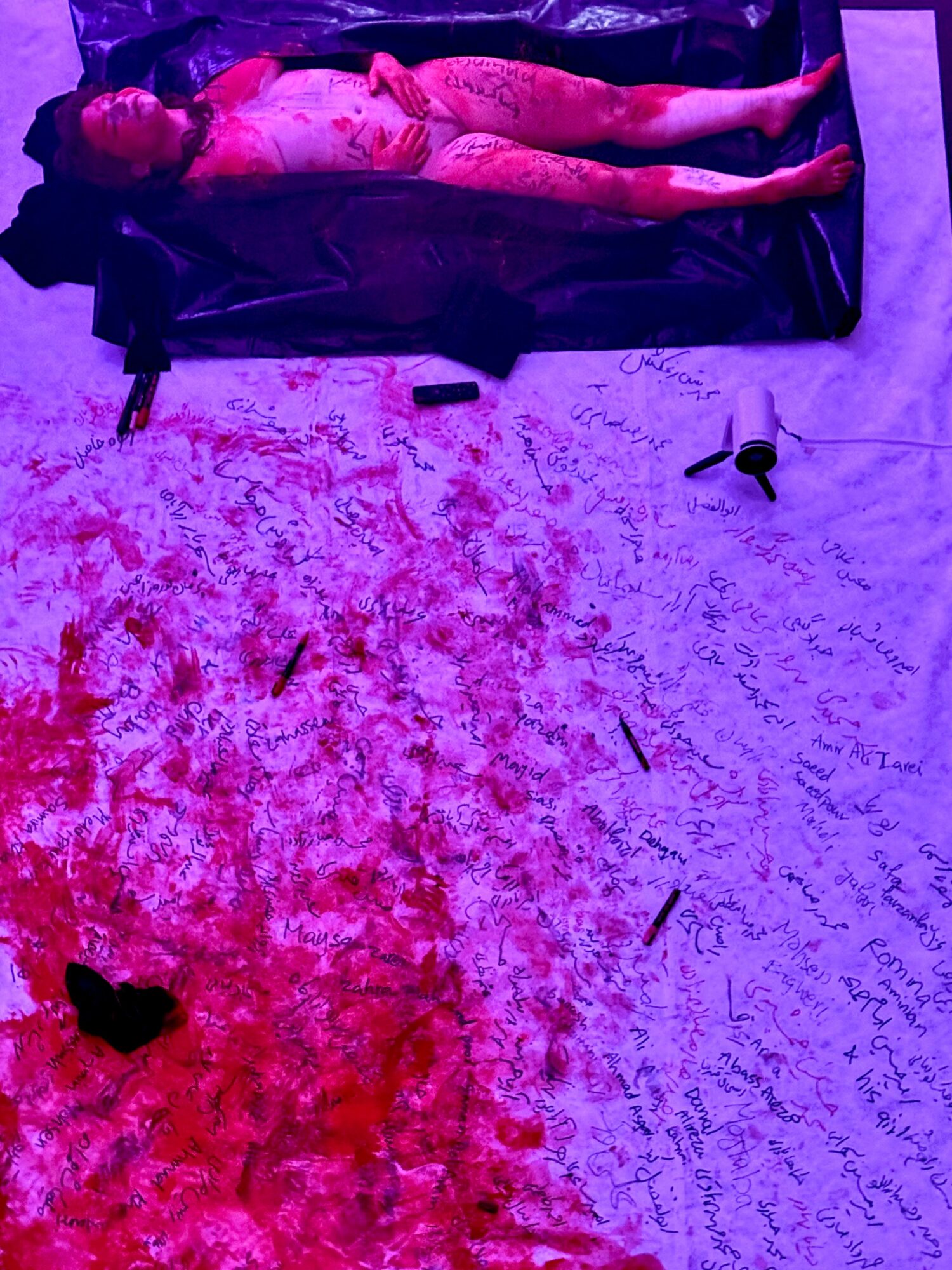 Person lying on a black couch with a blood-splattered floor and scattered objects around.