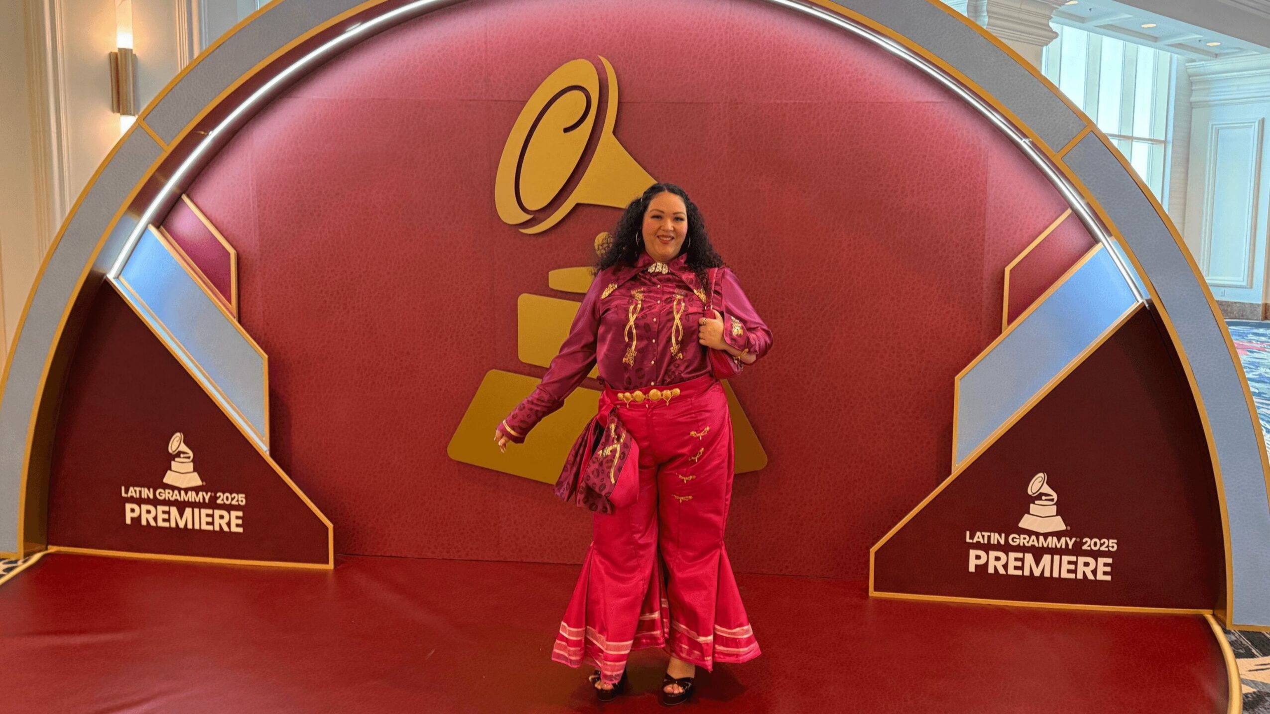 Woman standing in front of a large golden gramophone display at an event, with red background and promotional signage.