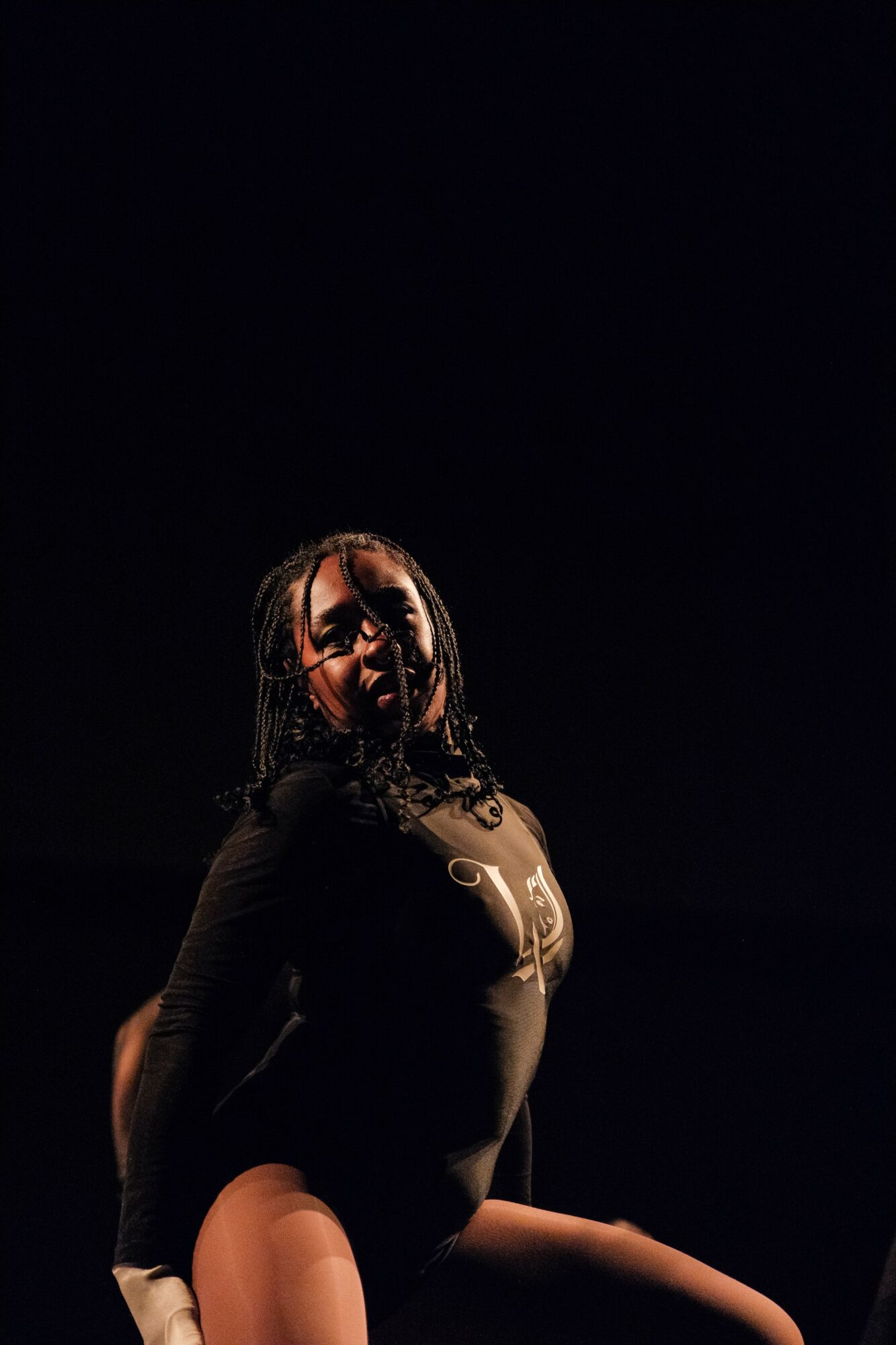 Person with glasses and wet hair, wearing a black outfit, standing in a dark environment.