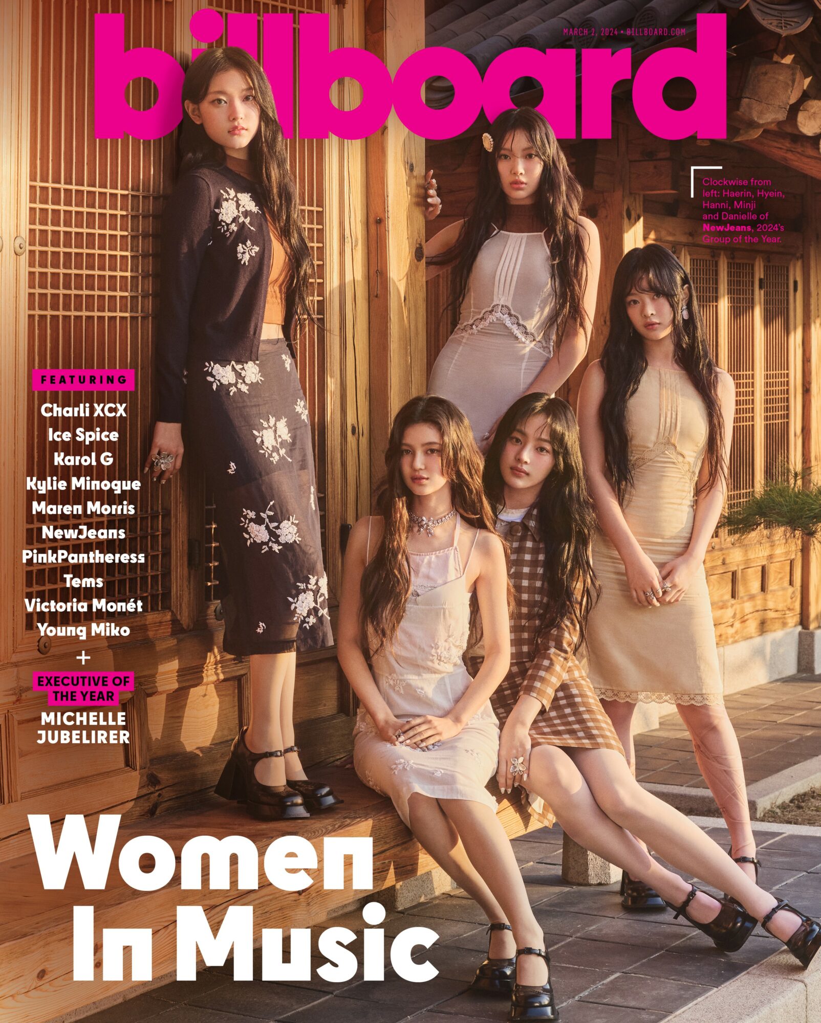 Five women pose outdoors in fashionable clothing, standing and sitting on a sidewalk with a wooden fence background.