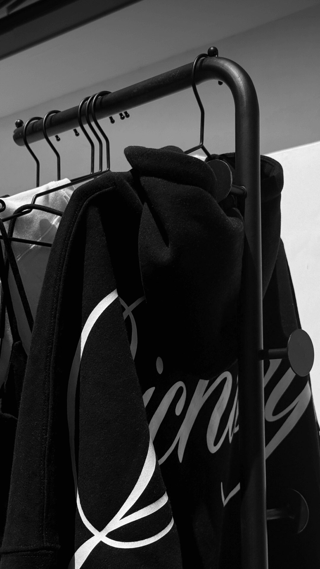 Black backpacks hanging on a metal rack in a store or closet.