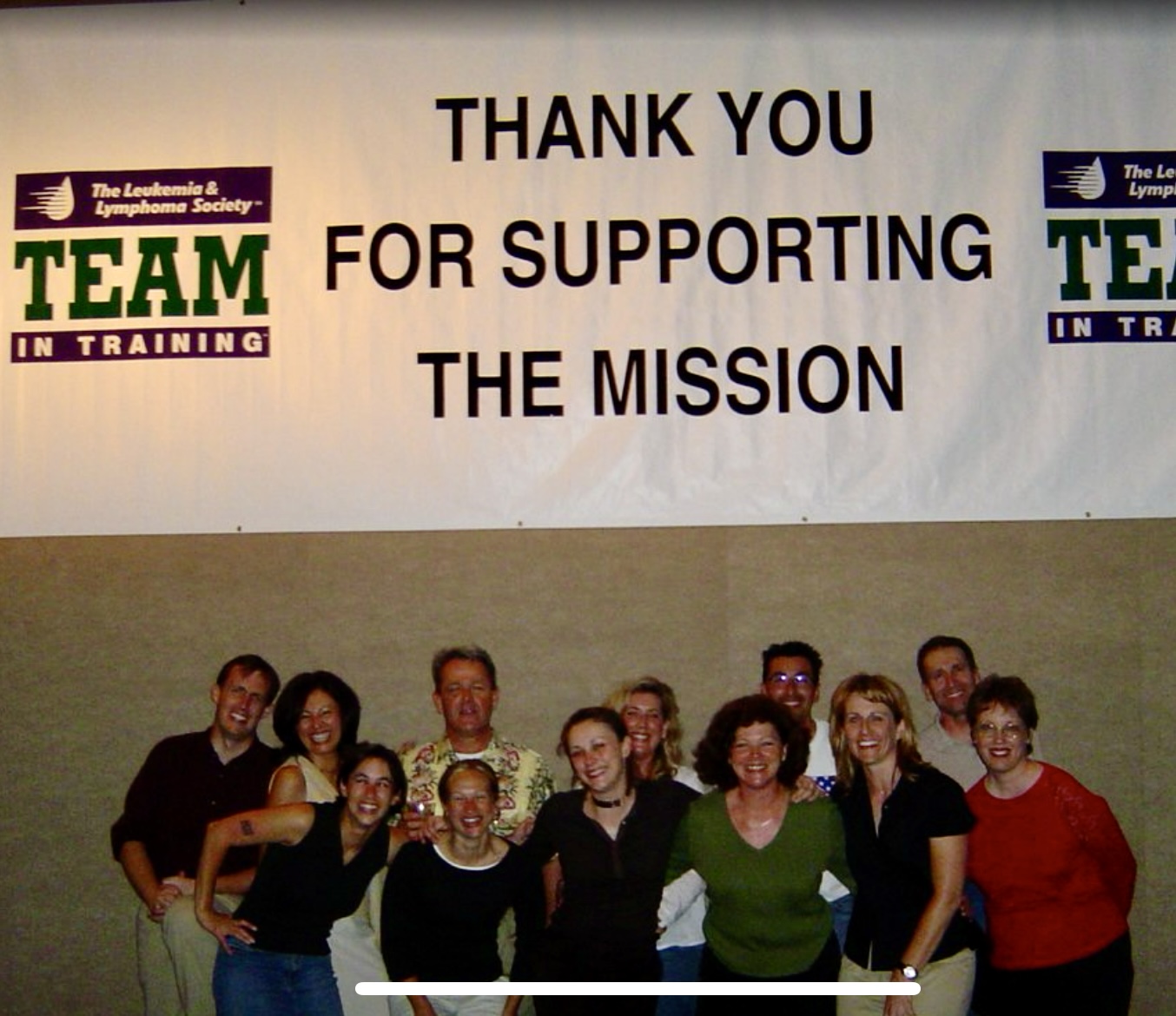 Group of people standing in front of a banner with text, smiling for a photo.