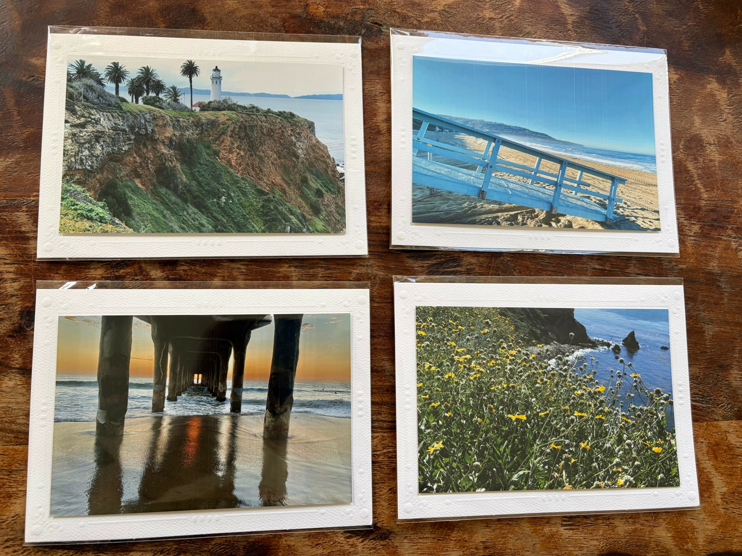 Four photographs of coastal scenes, including cliffs, a pier, a beach under a pier, and a shoreline with yellow flowers.