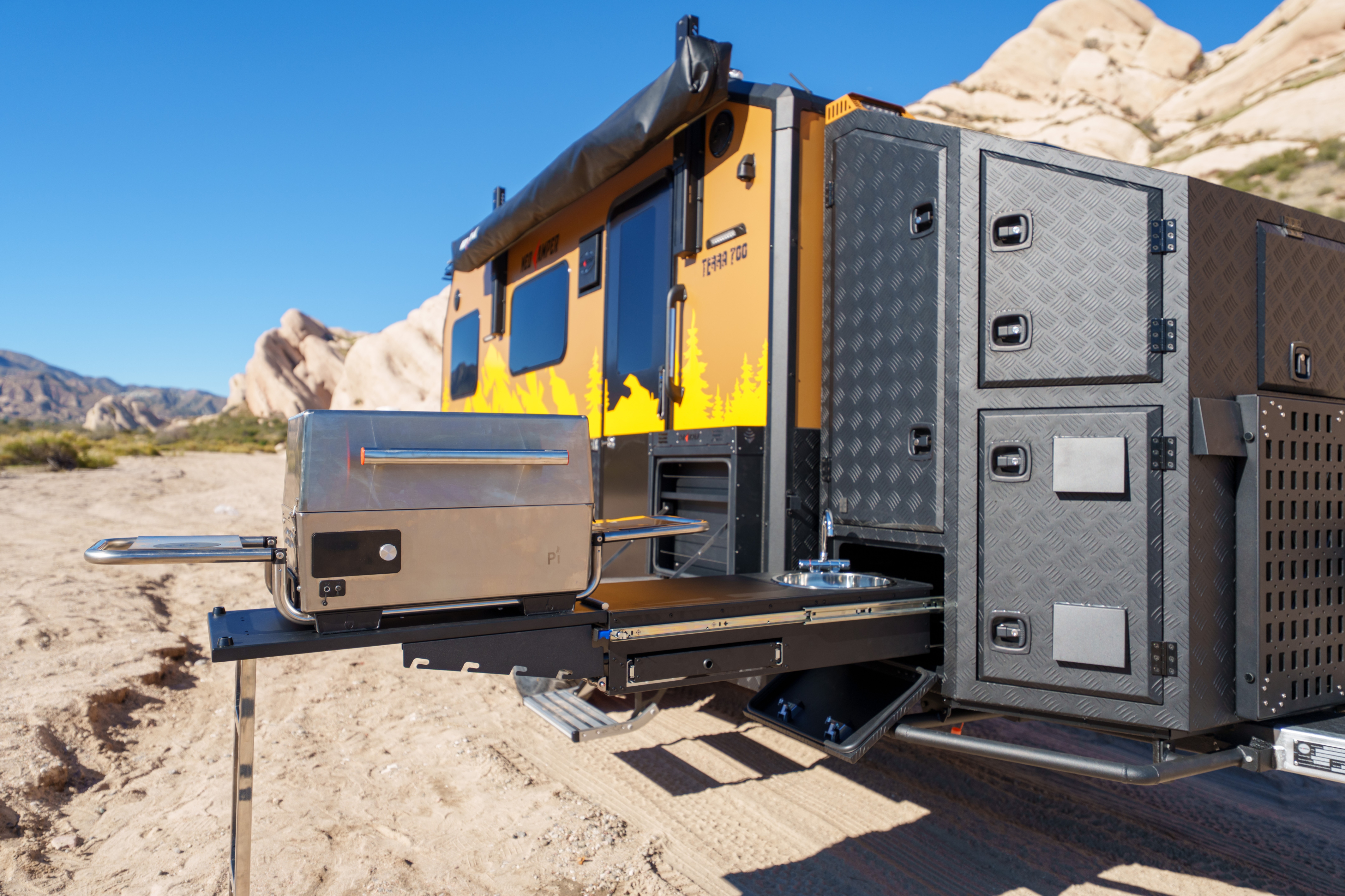 Yellow and black equipment with storage compartments on a rail track in a desert landscape.