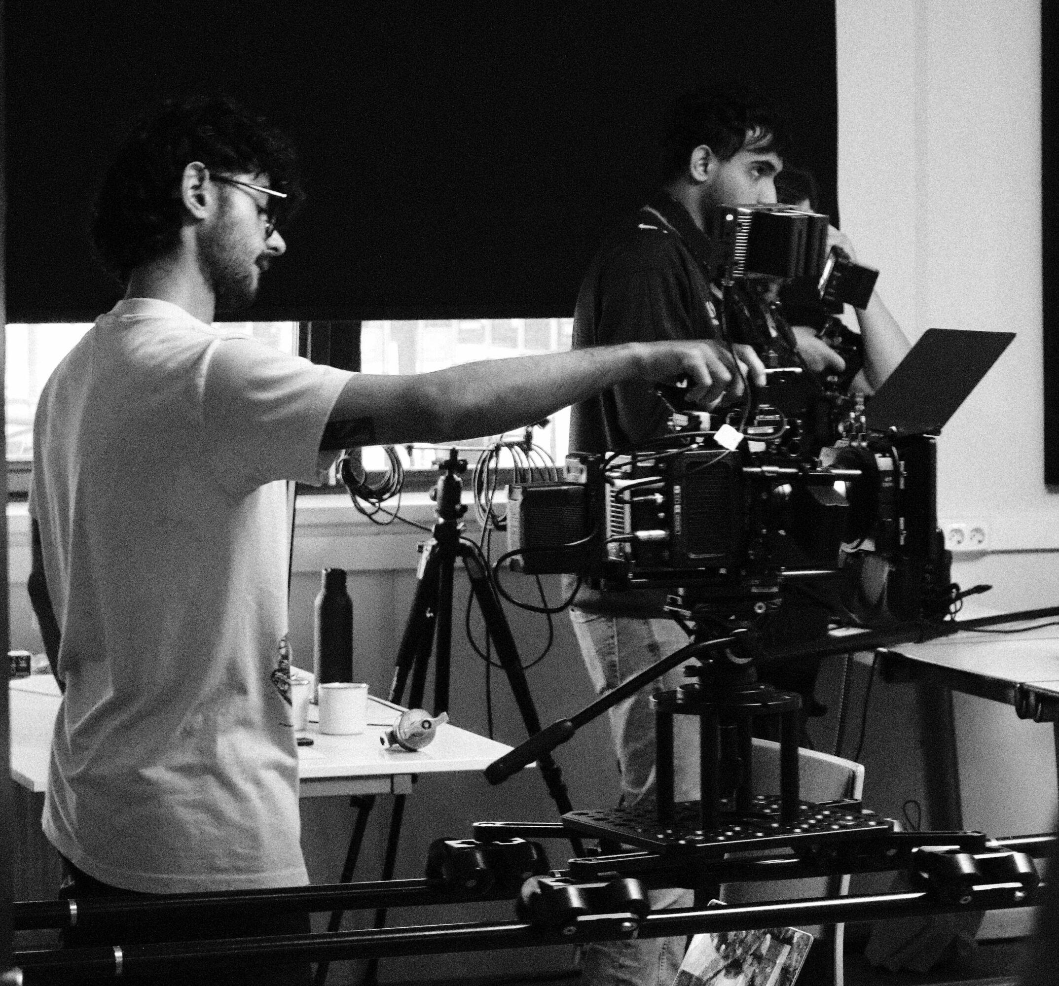 Two people operating a camera setup in a studio with equipment and a laptop.