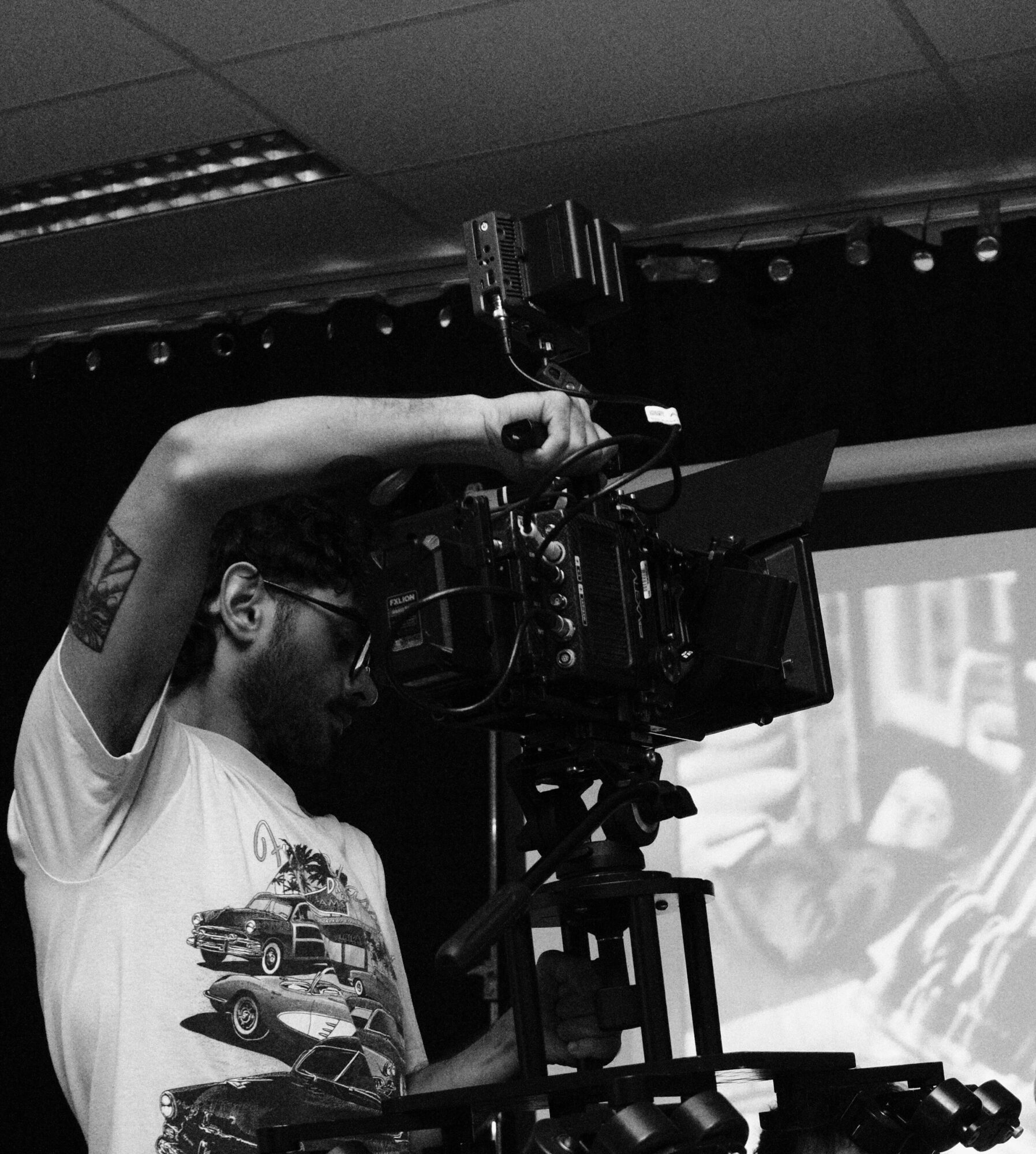 Person operating professional video camera in a studio with a screen in the background.