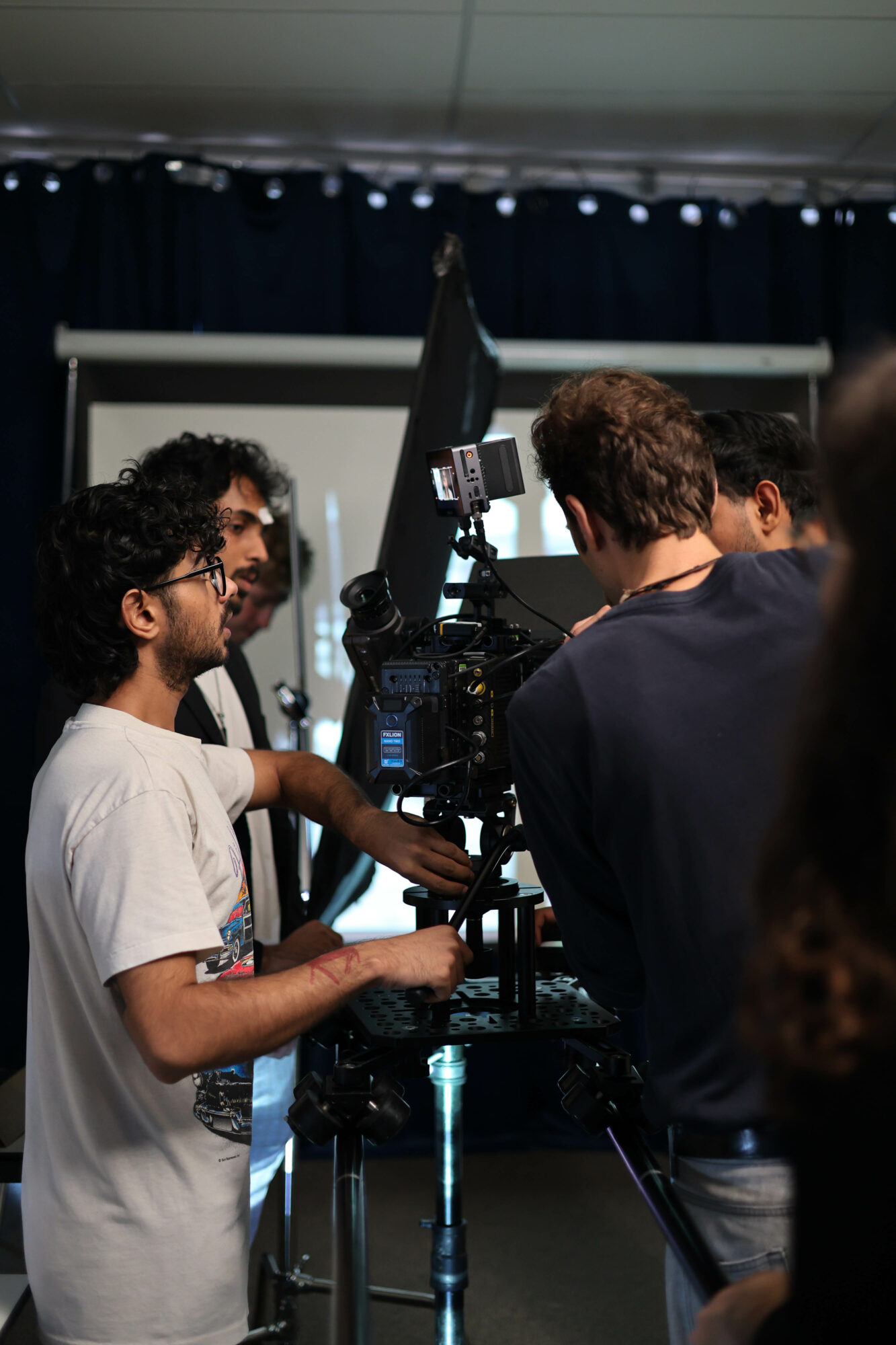 Group of people gathered around a camera and monitor, working together in a studio setting.