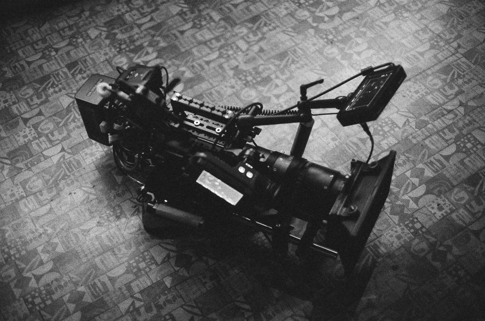 Camera on a patterned floor, with various controls and cables attached.