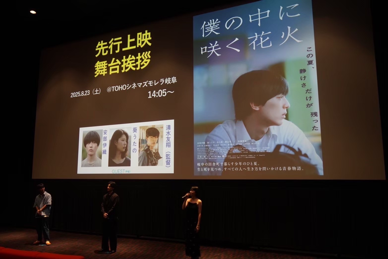 Large screen displays Japanese text, images of three people, and a woman with short hair looking to the side.