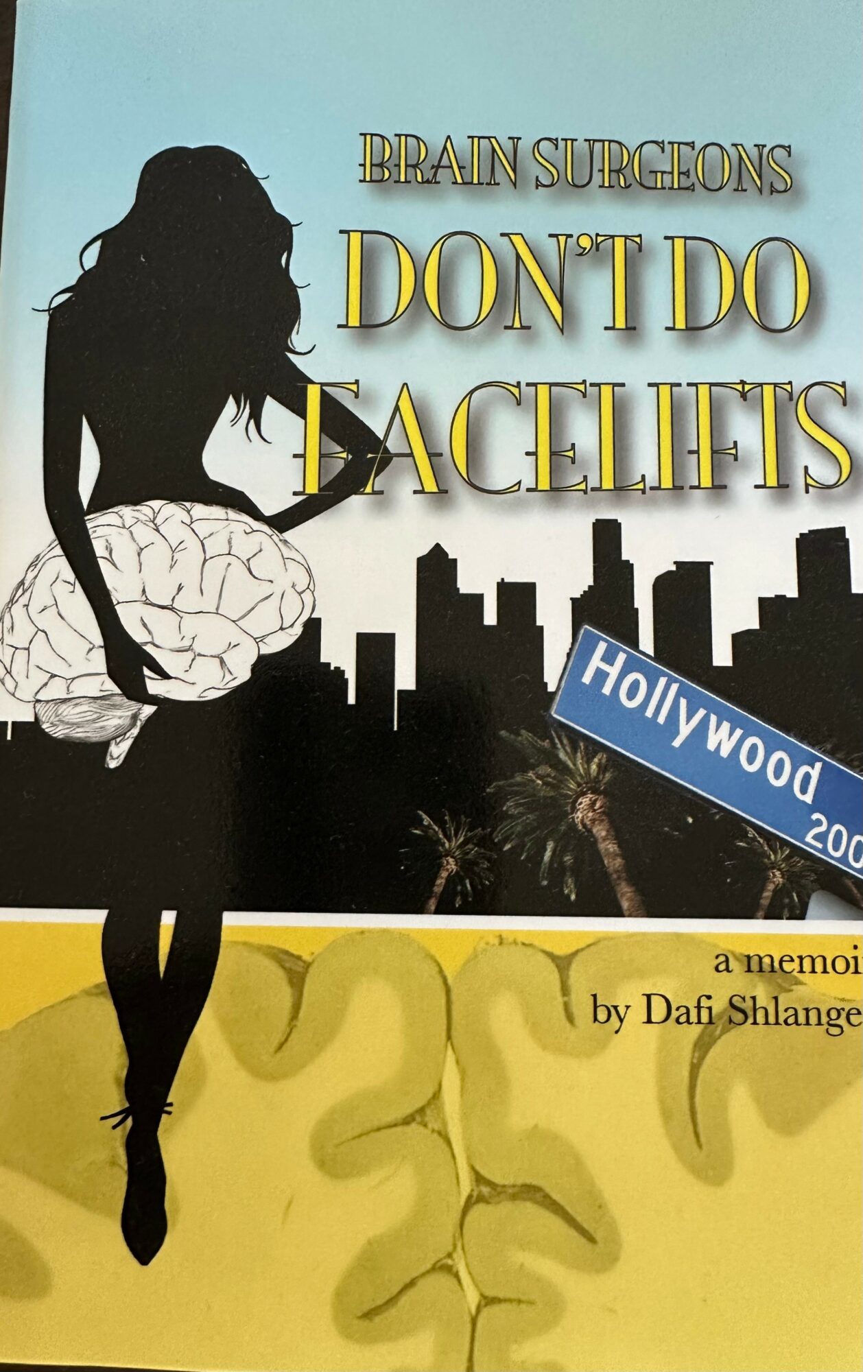 Silhouette of a woman sitting on a large brain with city skyline and Hollywood sign in background.