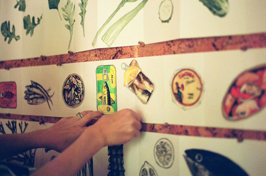 Person placing a sticker on a white wall decorated with various illustrated plant and animal stickers.