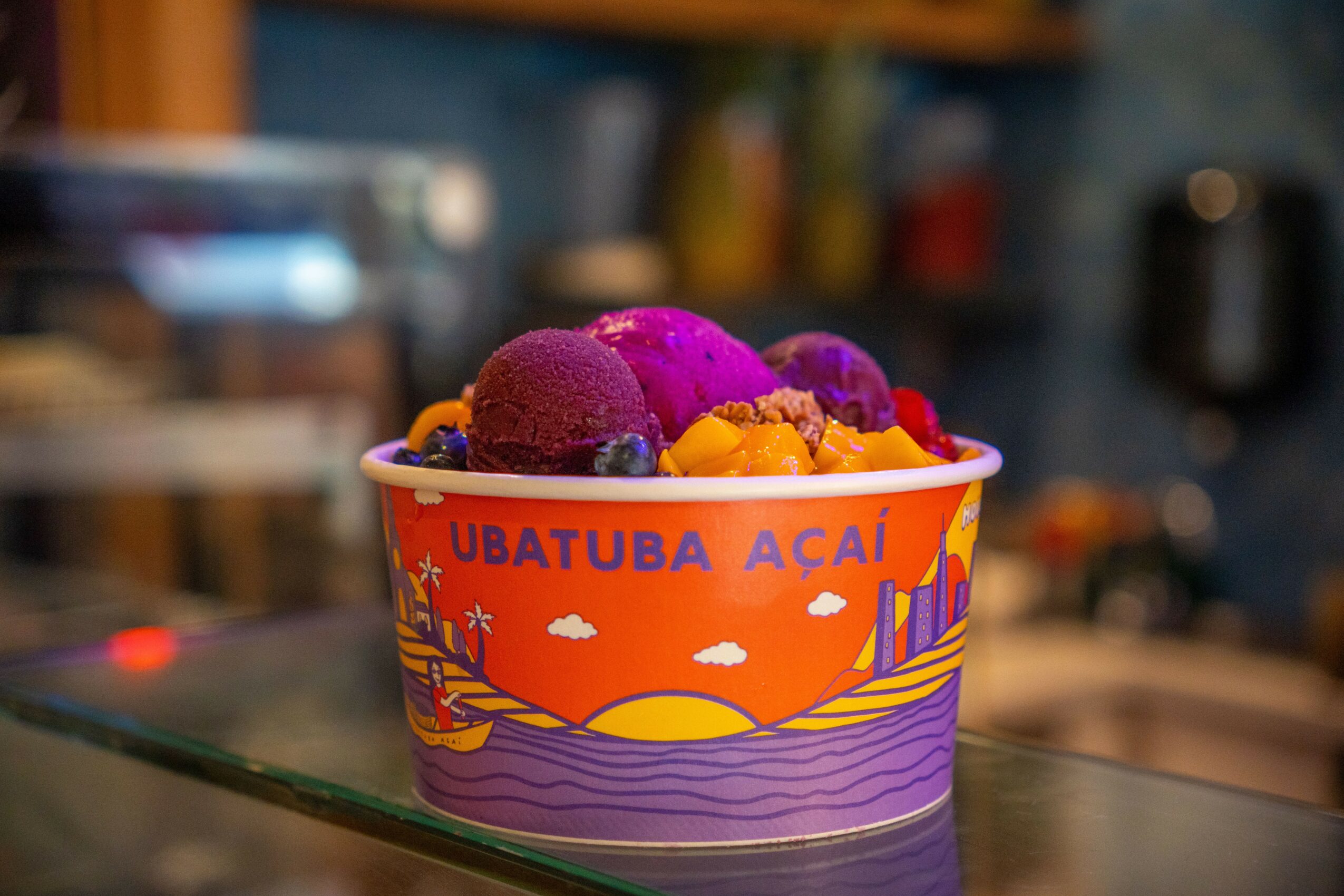 Cup with colorful acai and fruit toppings, decorated with a sunset and ocean design.