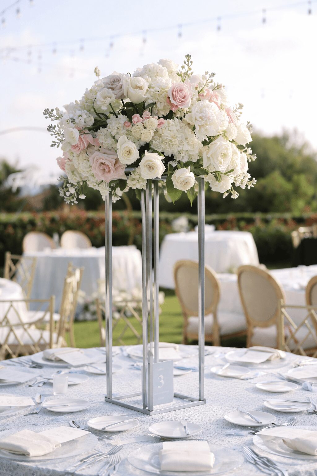 Elegant floral centerpiece with white and pink flowers on a table at an outdoor event.
