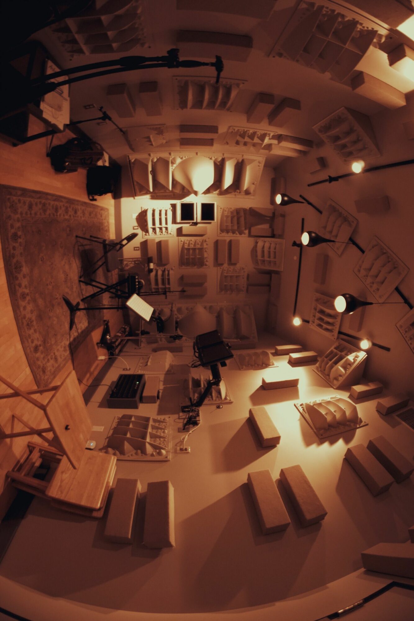 Room with shelves, music stands, and chairs, illuminated by warm lighting, with a curved ceiling and wooden floor.