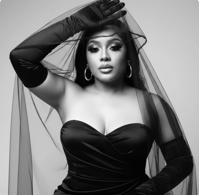 Woman with long hair, wearing a strapless dress, hoop earrings, and gloves, holding a veil over her head.