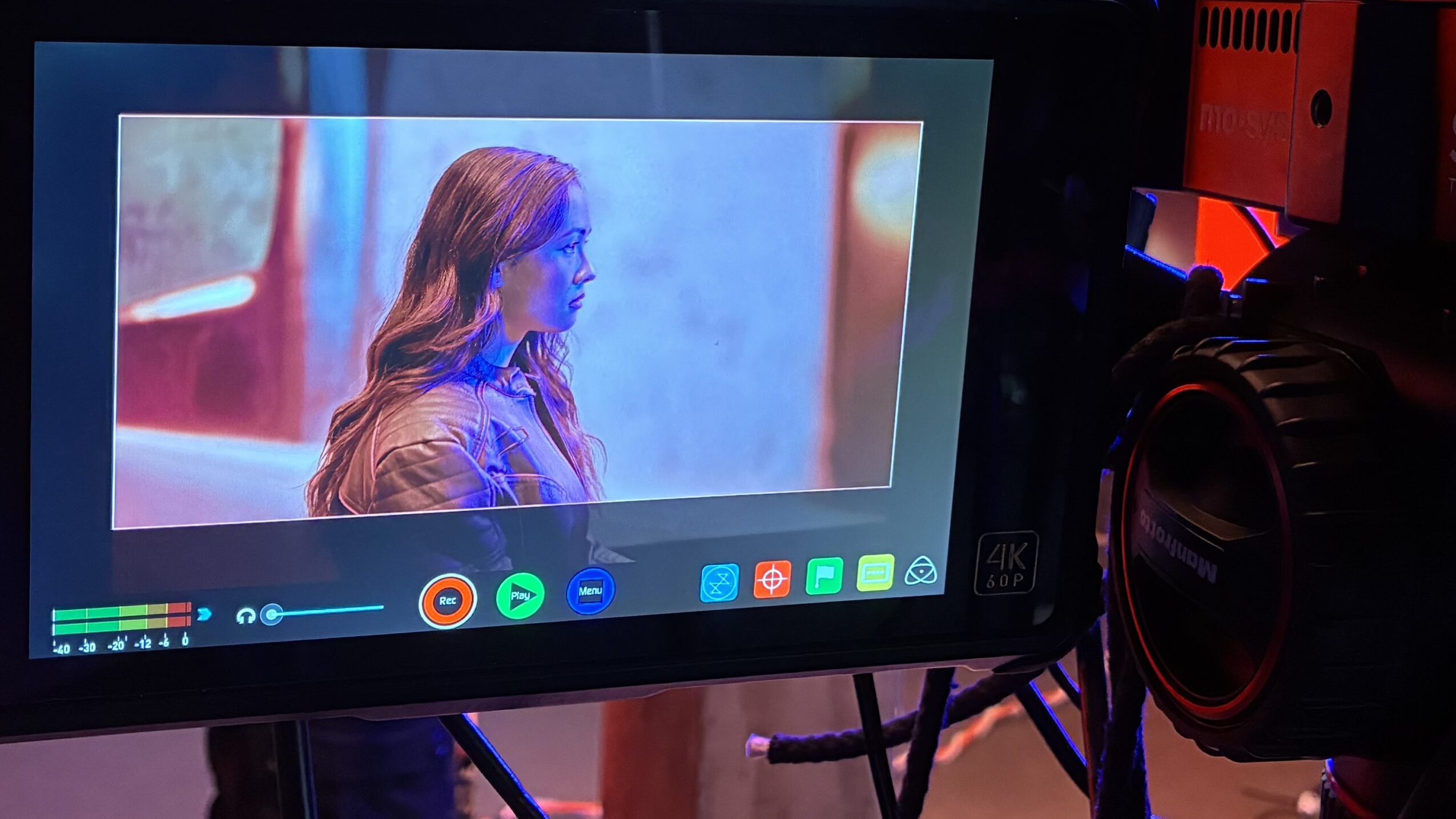 Monitor displaying a woman with long hair in profile, with colorful background, on a video recording device.