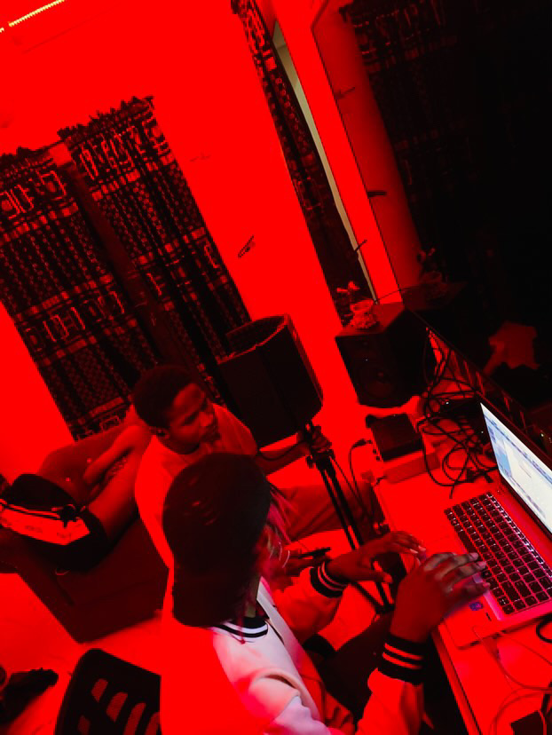 People working at a table with laptops in a room illuminated by red light.