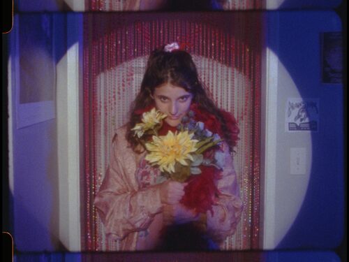 Girl holding a bouquet of yellow flowers, standing in front of a red curtain with a spotlight effect.