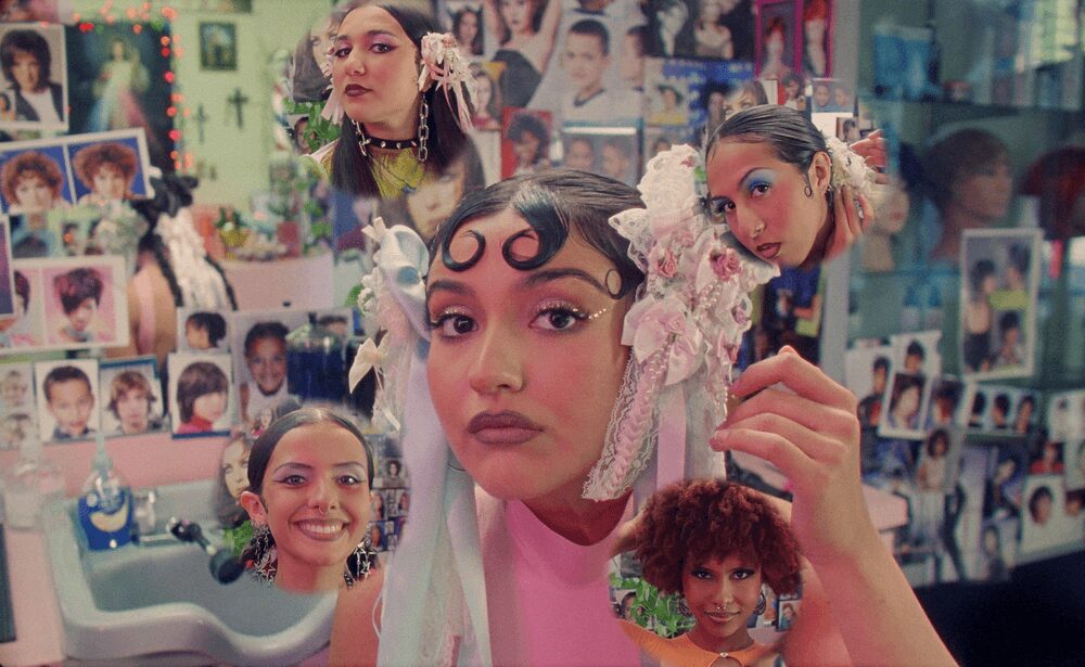 Person with multiple small portraits and dolls around their head, holding a doll, in a room with photo walls.