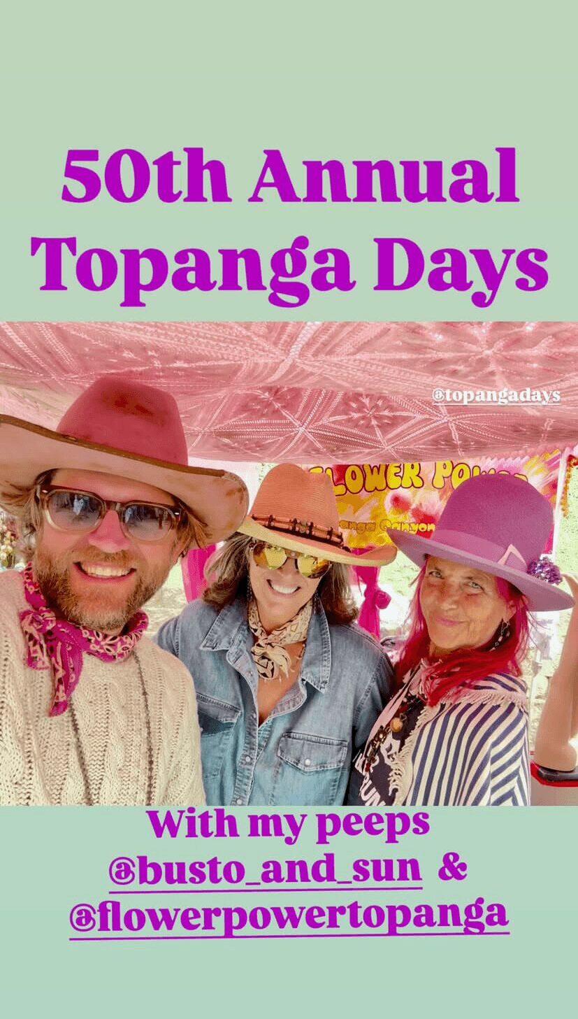 Group of three people wearing hats and sunglasses, smiling outdoors during daytime.