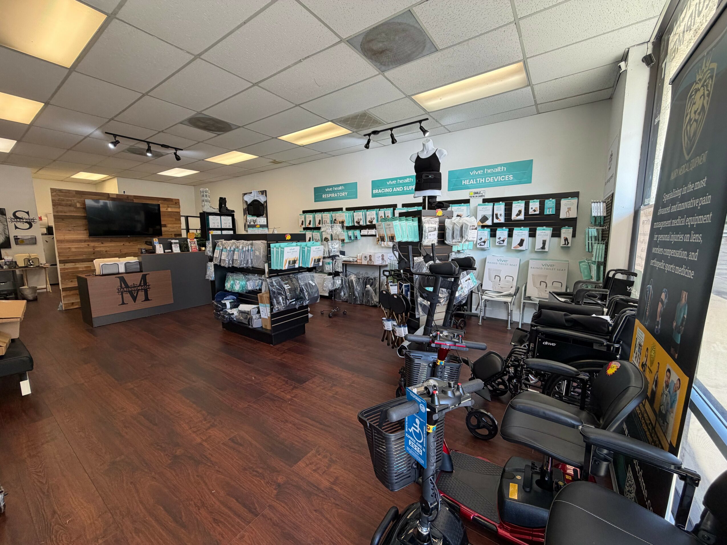 Store interior with display shelves, chairs, and a counter area, featuring wood flooring and ceiling lights.