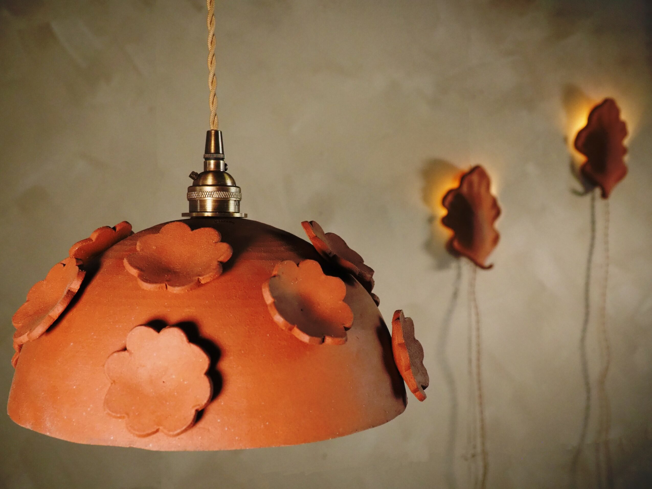 Pendant lamp with cloud-shaped cutouts, hanging from ceiling, with three cloud-shaped wall lights in background.