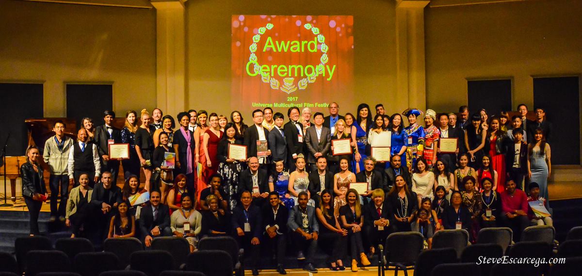 Large group of people on stage at an award ceremony, with a screen displaying 'Award Ceremony' in the background.
