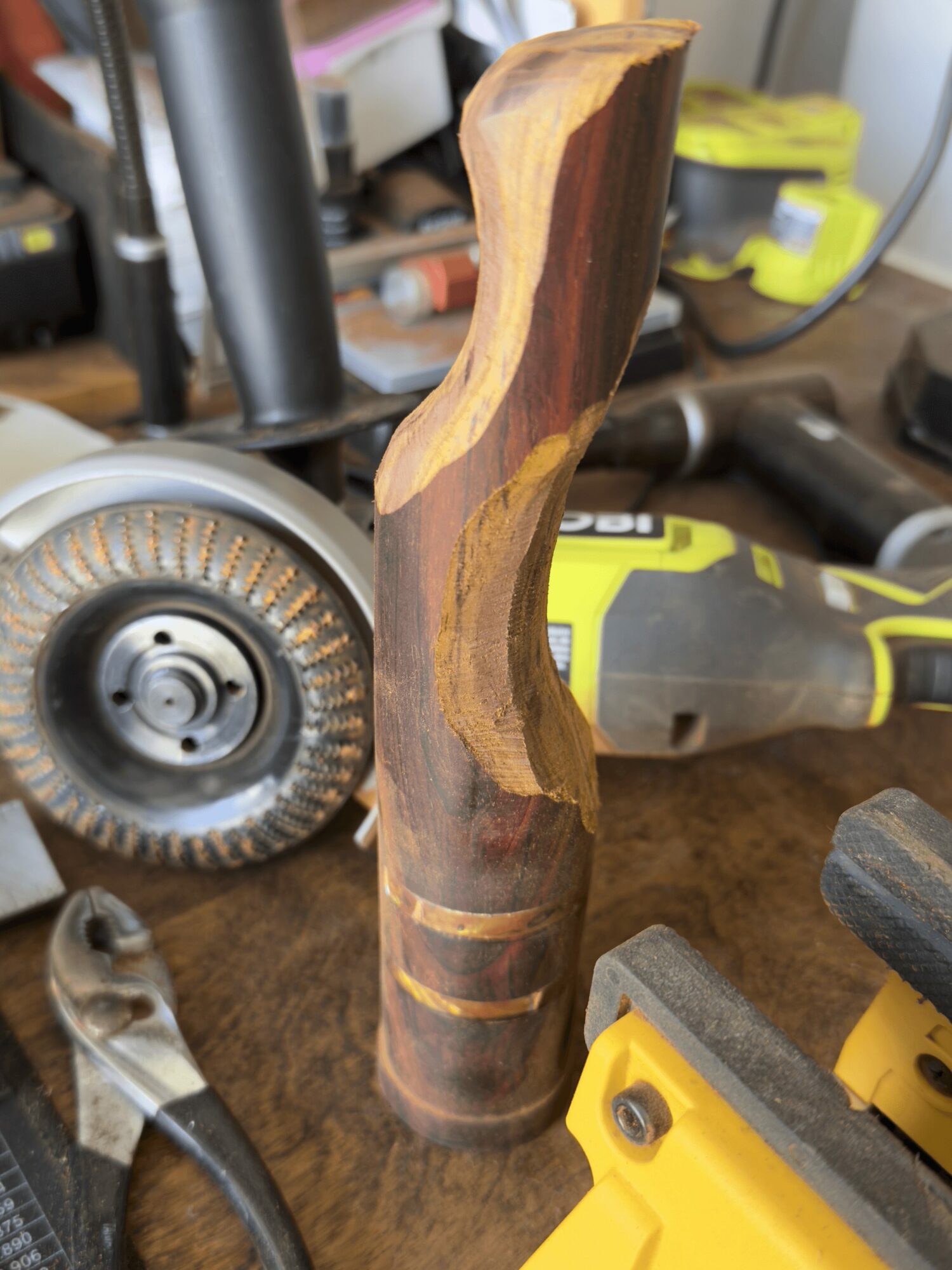 Wooden carving with a curved shape and natural wood grain, placed on a workbench with tools around.