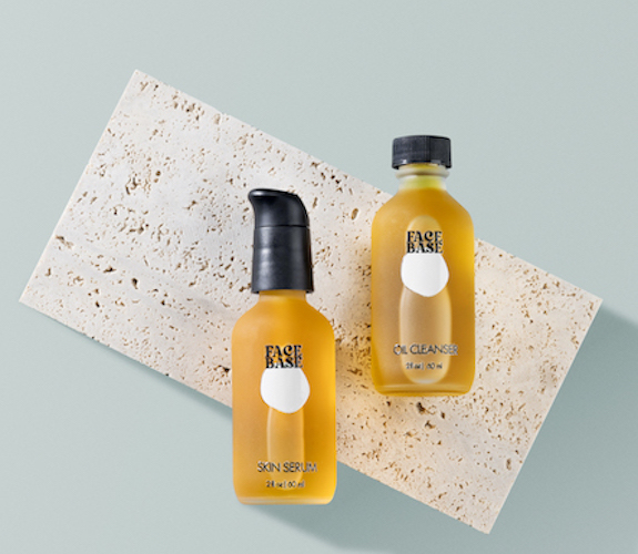 Two yellow bottles of skincare products on a beige textured surface with a light blue background.