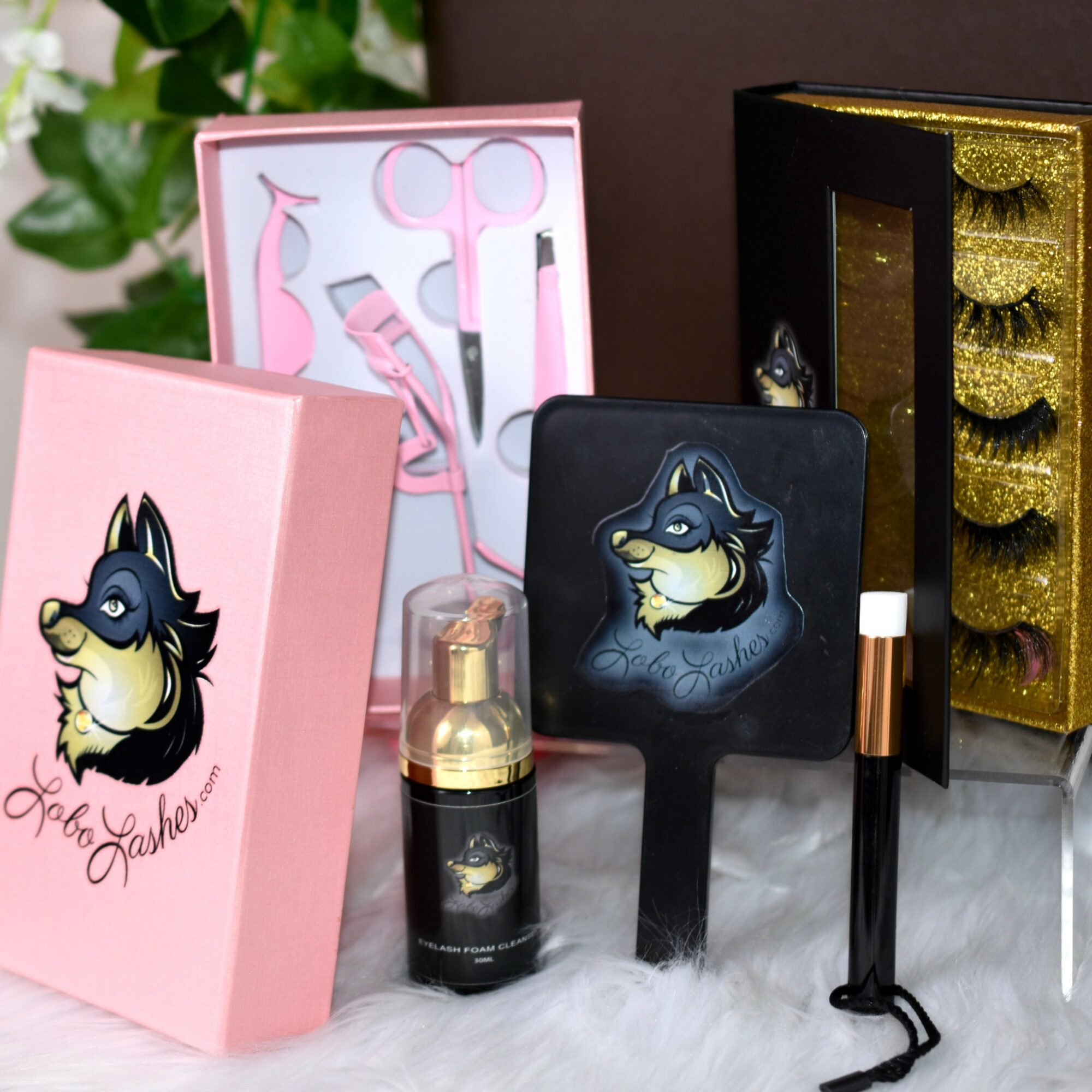 Collection of beauty and grooming products, including a pink box, a black box with false eyelashes, and a small mirror with a wolf illustration.