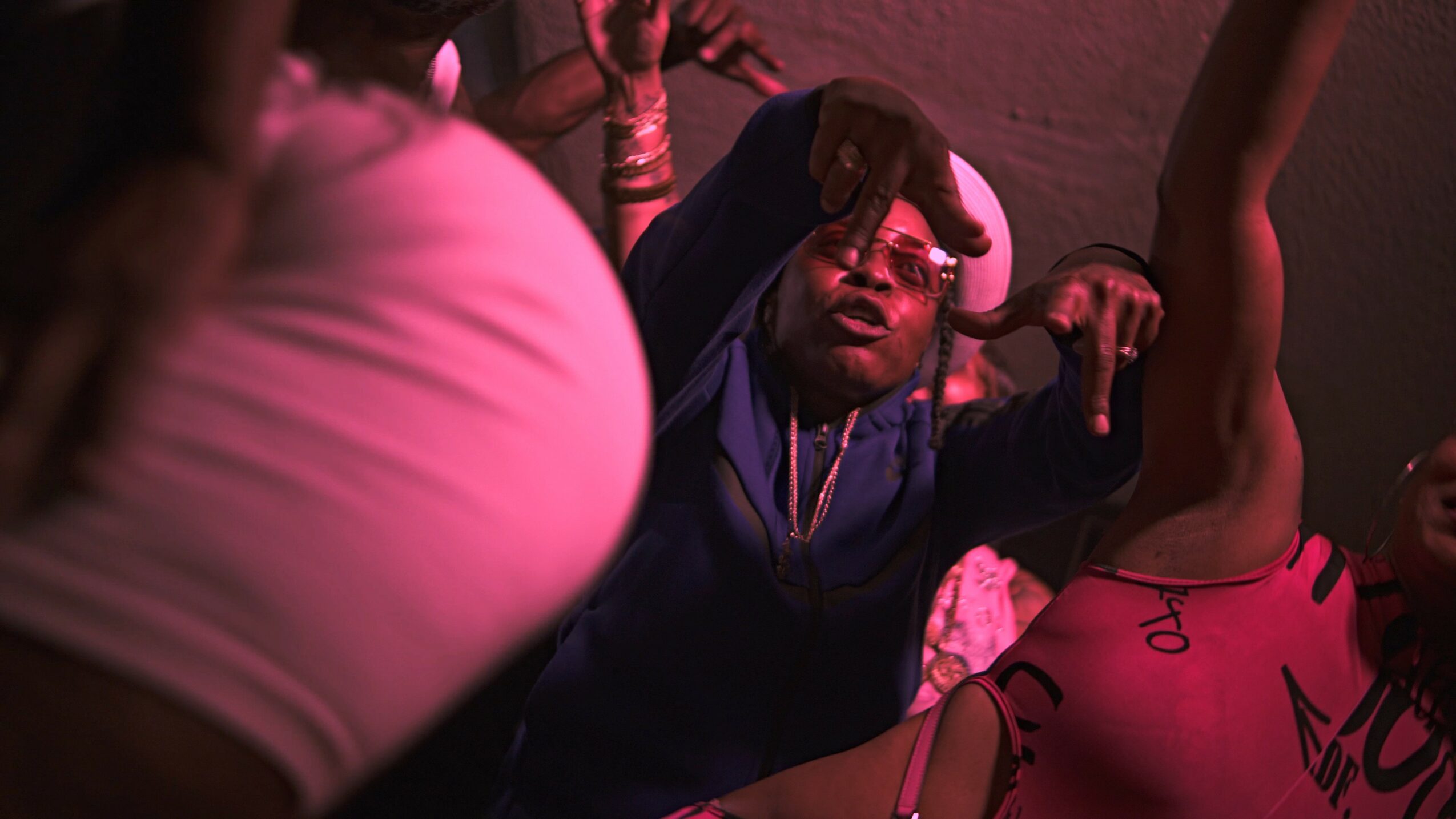 Person lying on the floor with another person reaching over, in a dimly lit setting.