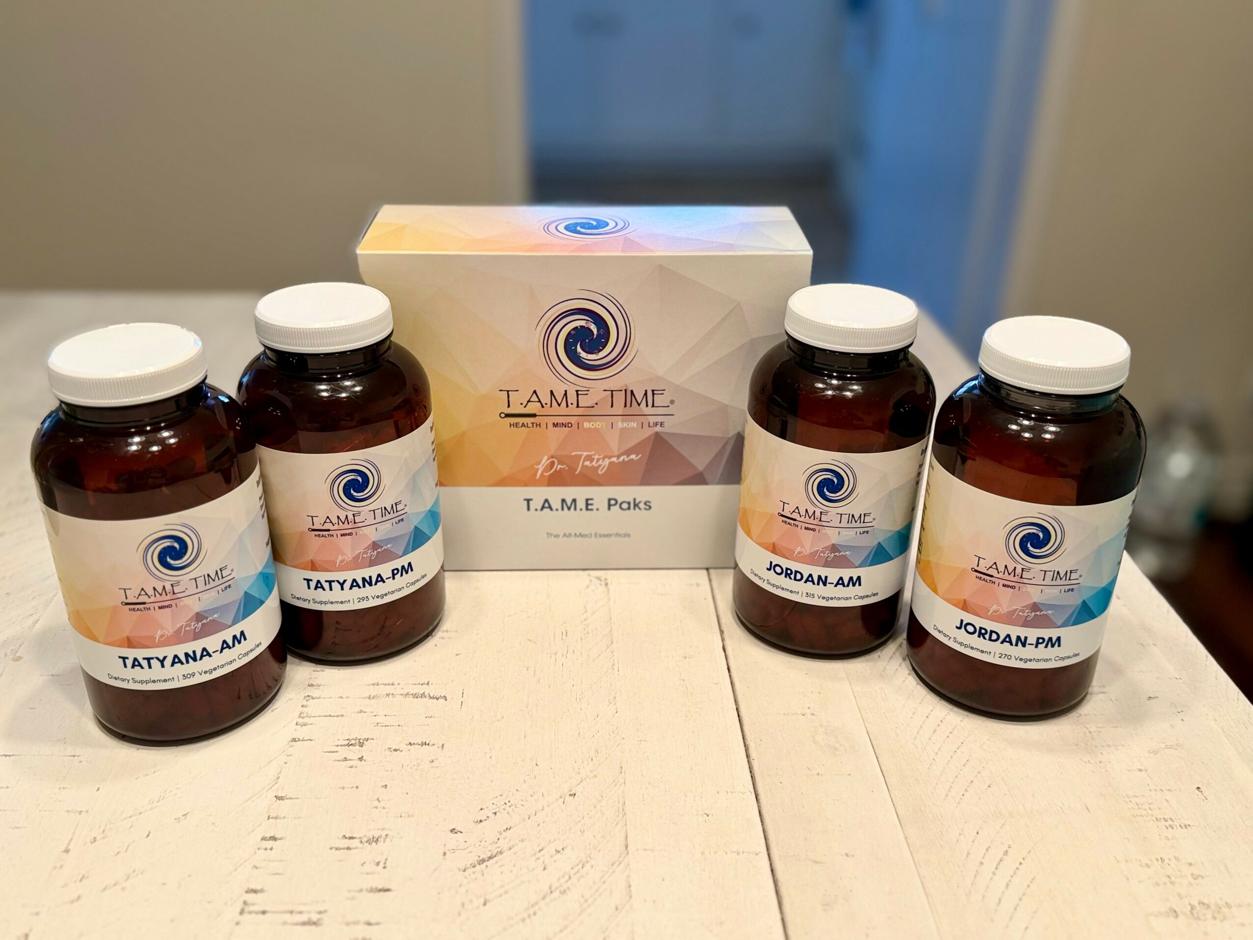 Four brown bottles with white caps and a box behind them on a white surface.