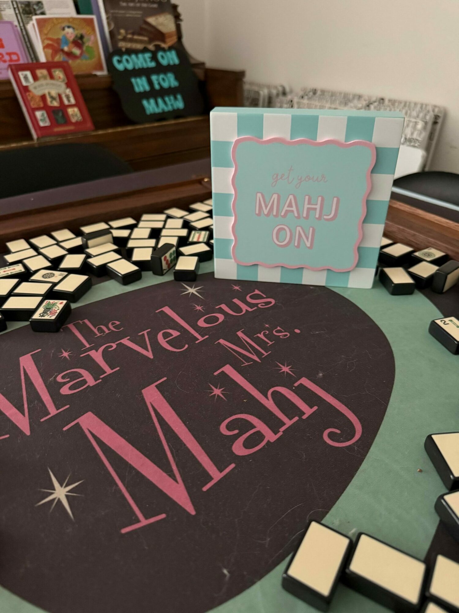Table with black and white dominoes, a sign, and a mat with pink and white text about a wedding event.
